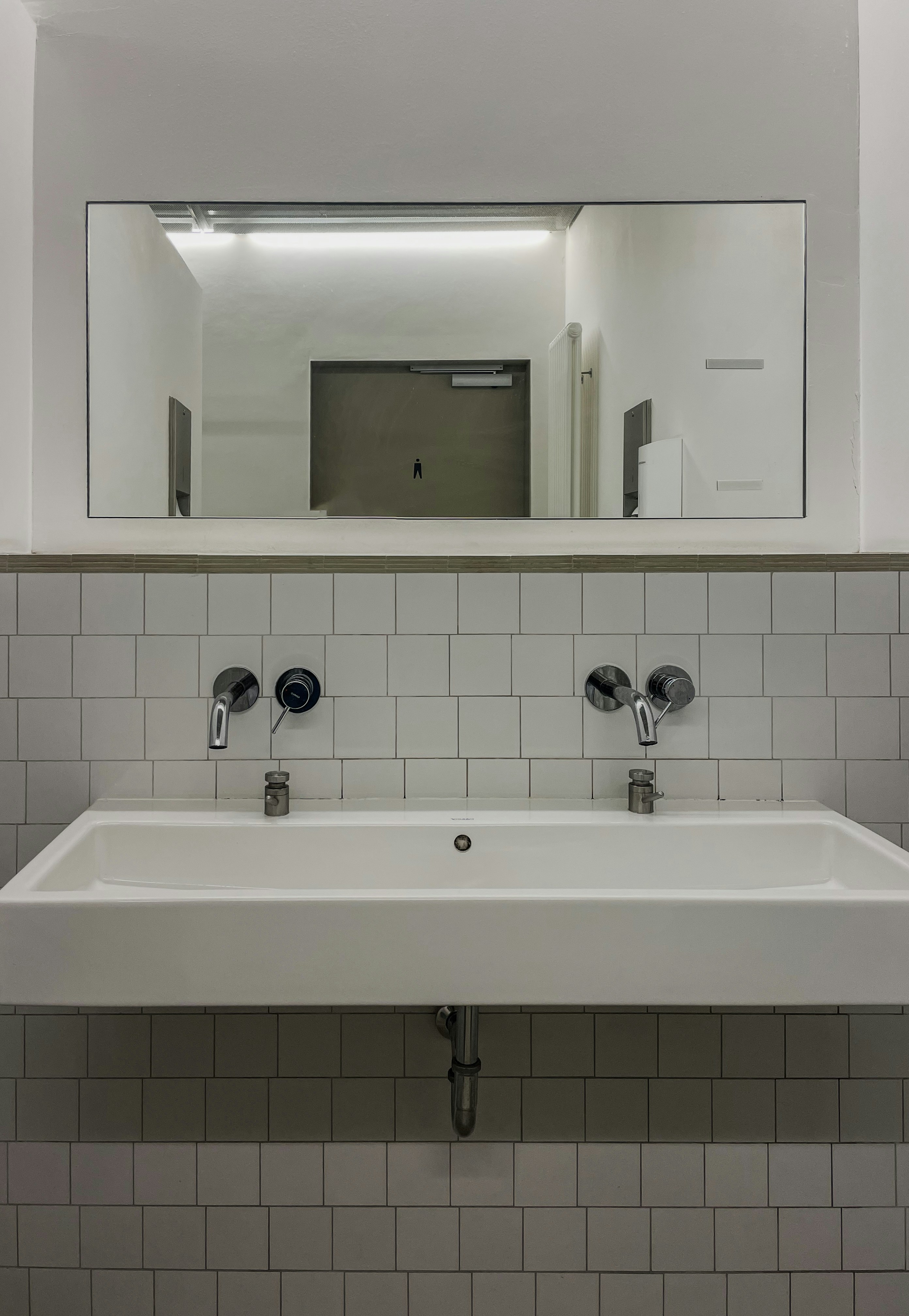 A white double sink with faucets and a mirror.