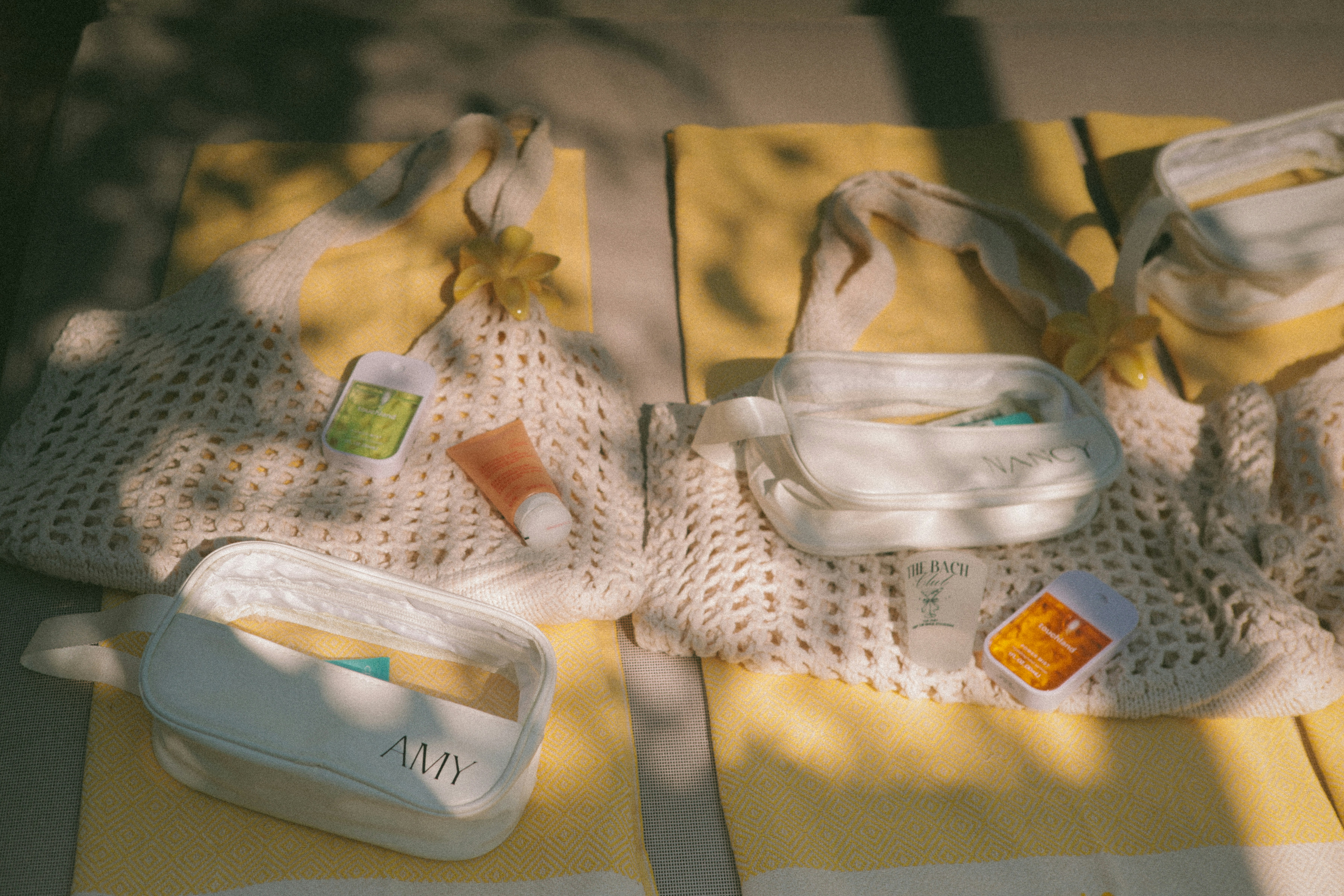 Deux sacs en maille blanc avec des accents jaunes et des articles de toilette.