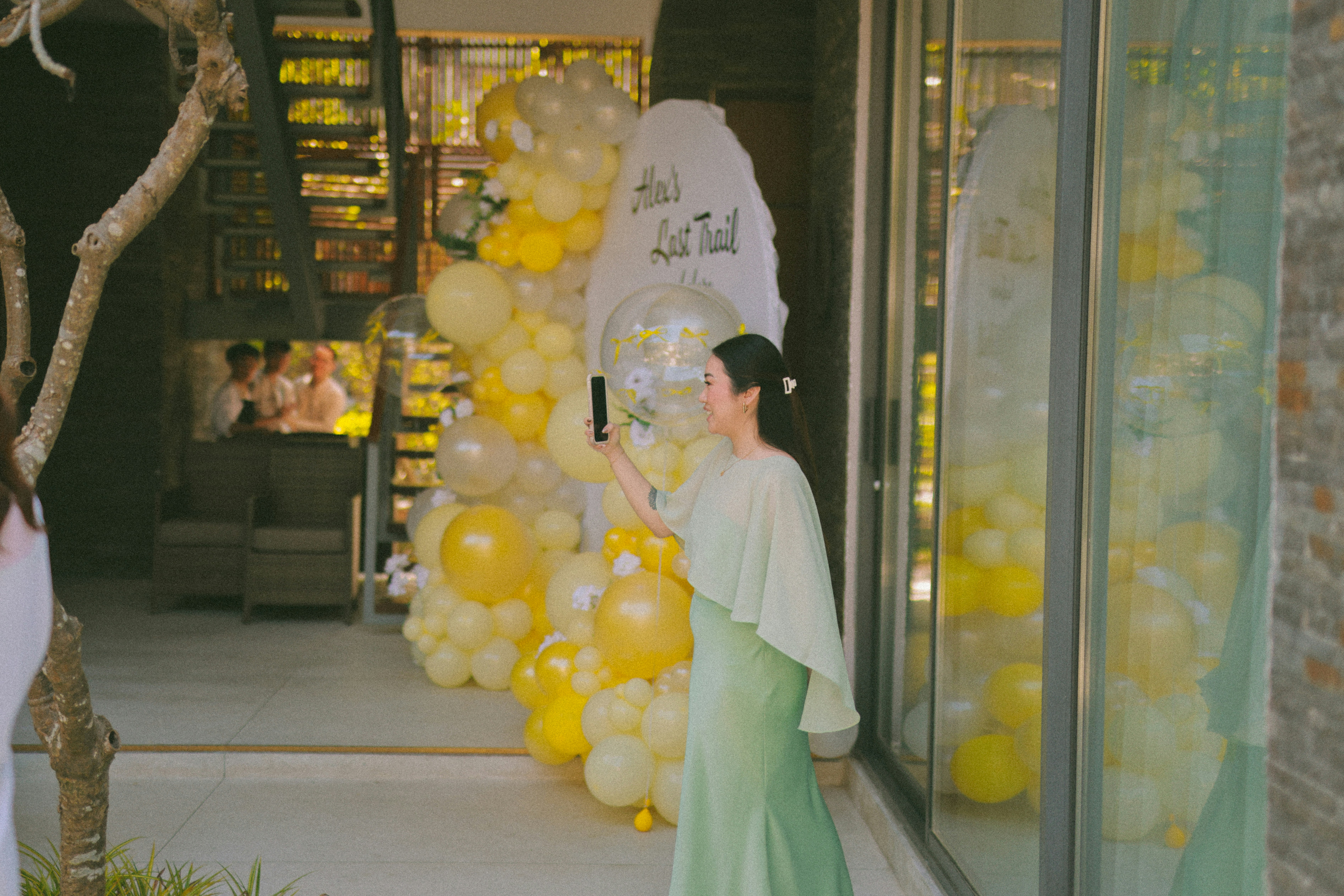 Woman in green dress takes a selfie with balloons.