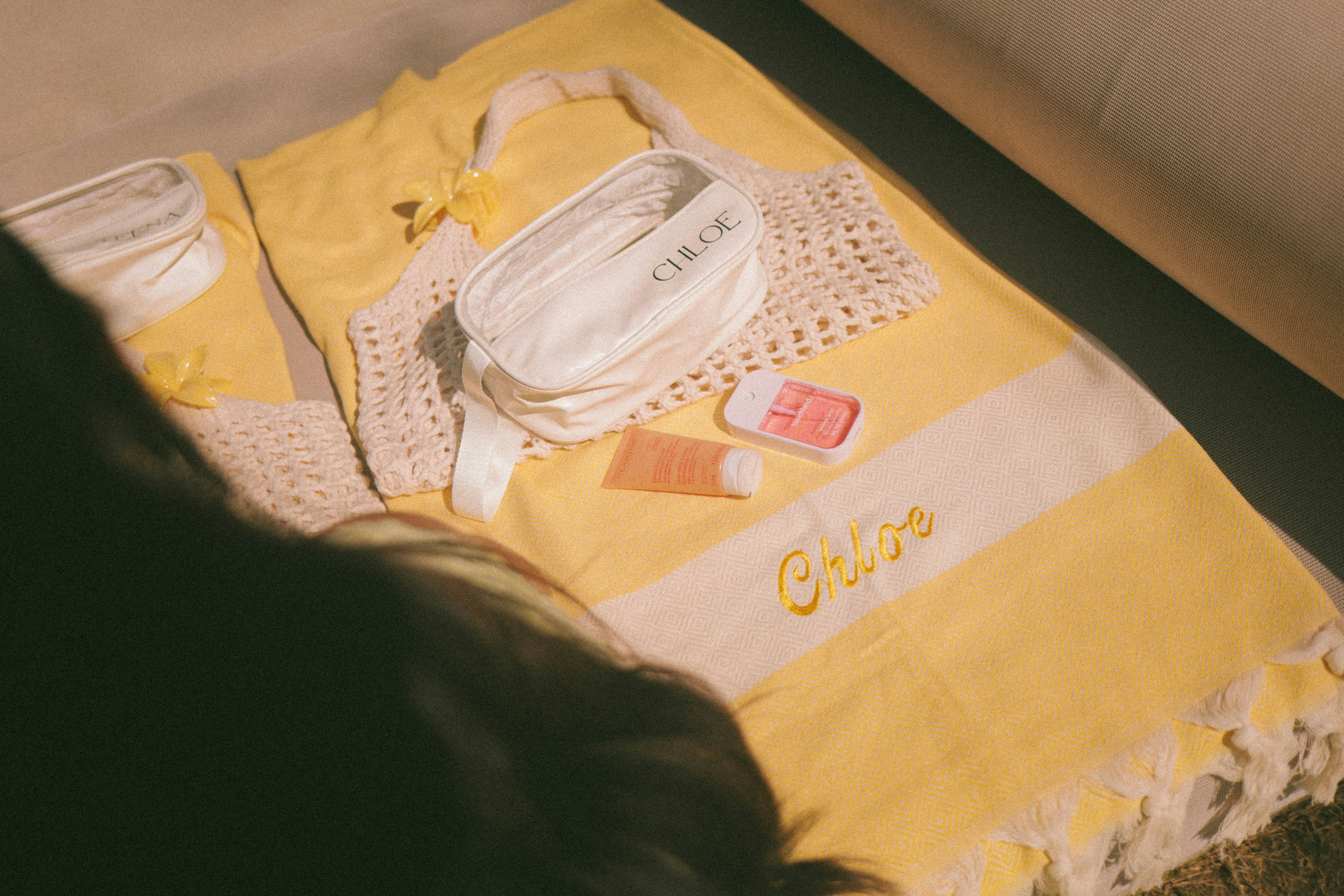 Beach essentials laid out on a yellow striped towel.