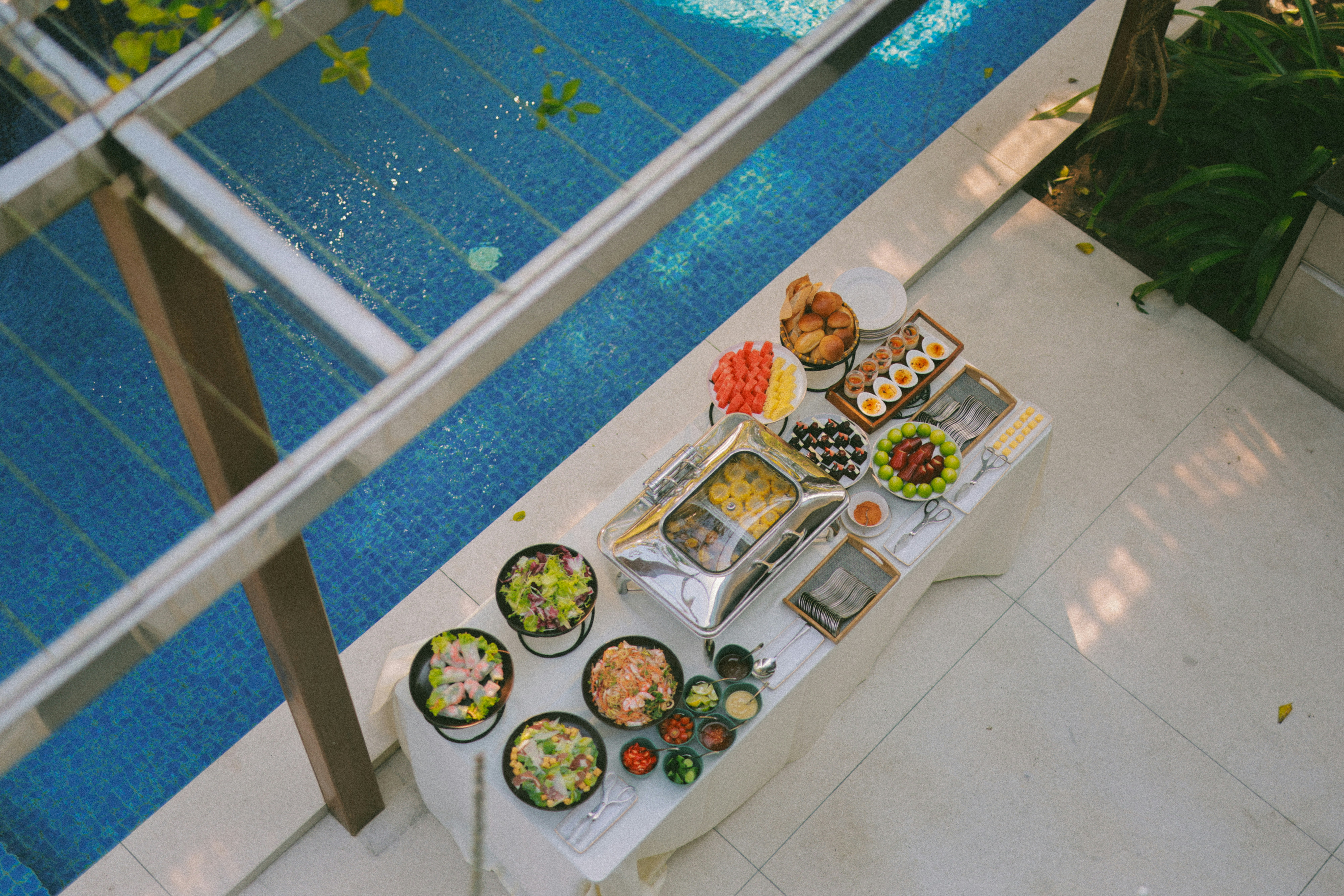 Buffet table with assorted food dishes by the pool.