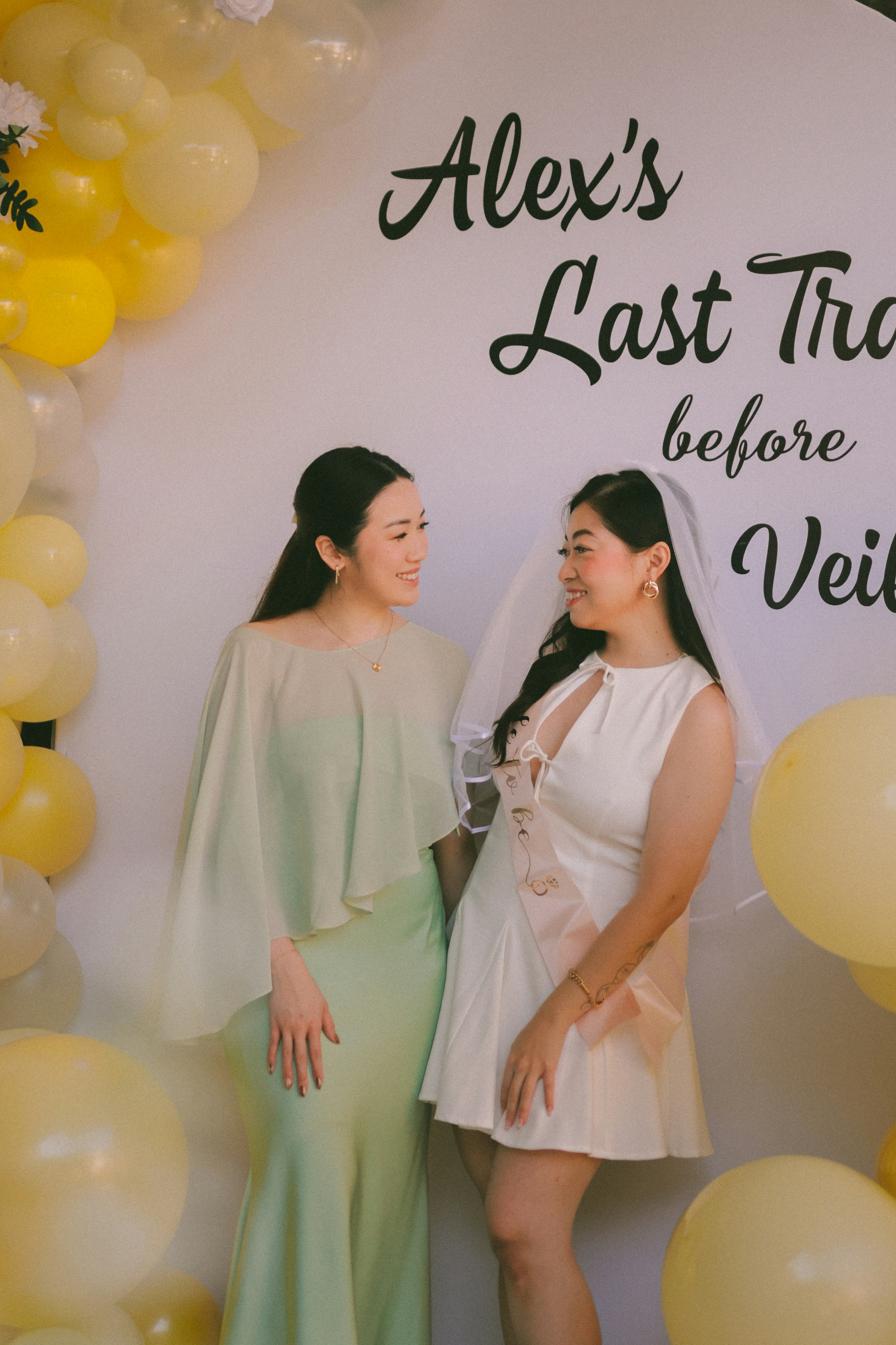 Dos mujeres sonriendo en una despedida de soltera con globos.