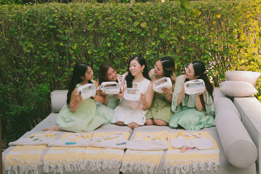 Five women in pastel dresses share food outdoors