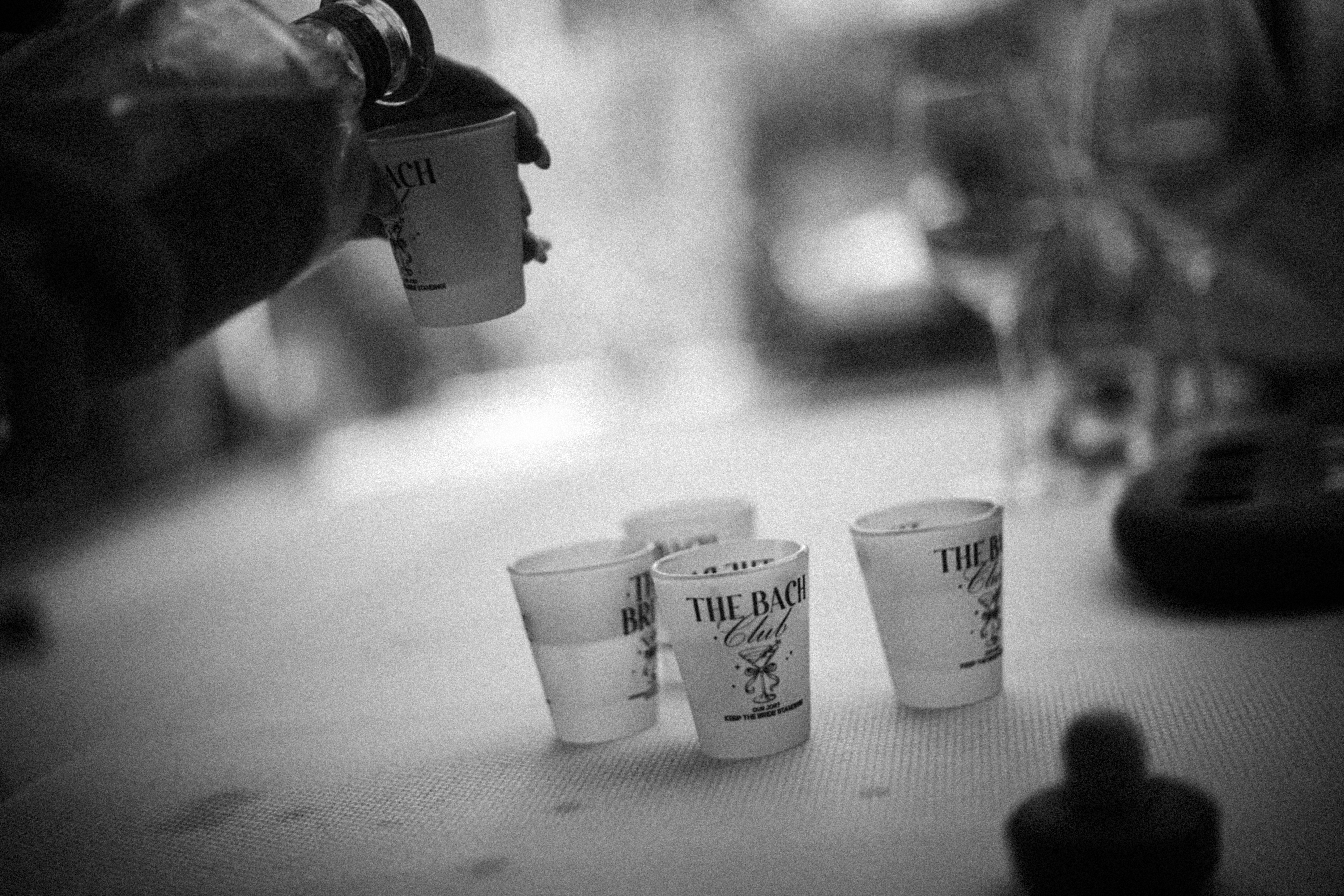 A hand pours liquid into small plastic cups