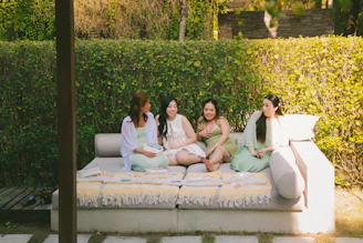 Four women relax on an outdoor lounge sofa.