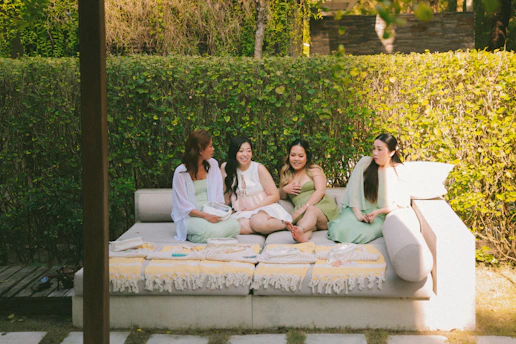 Four women relax on an outdoor lounge sofa.