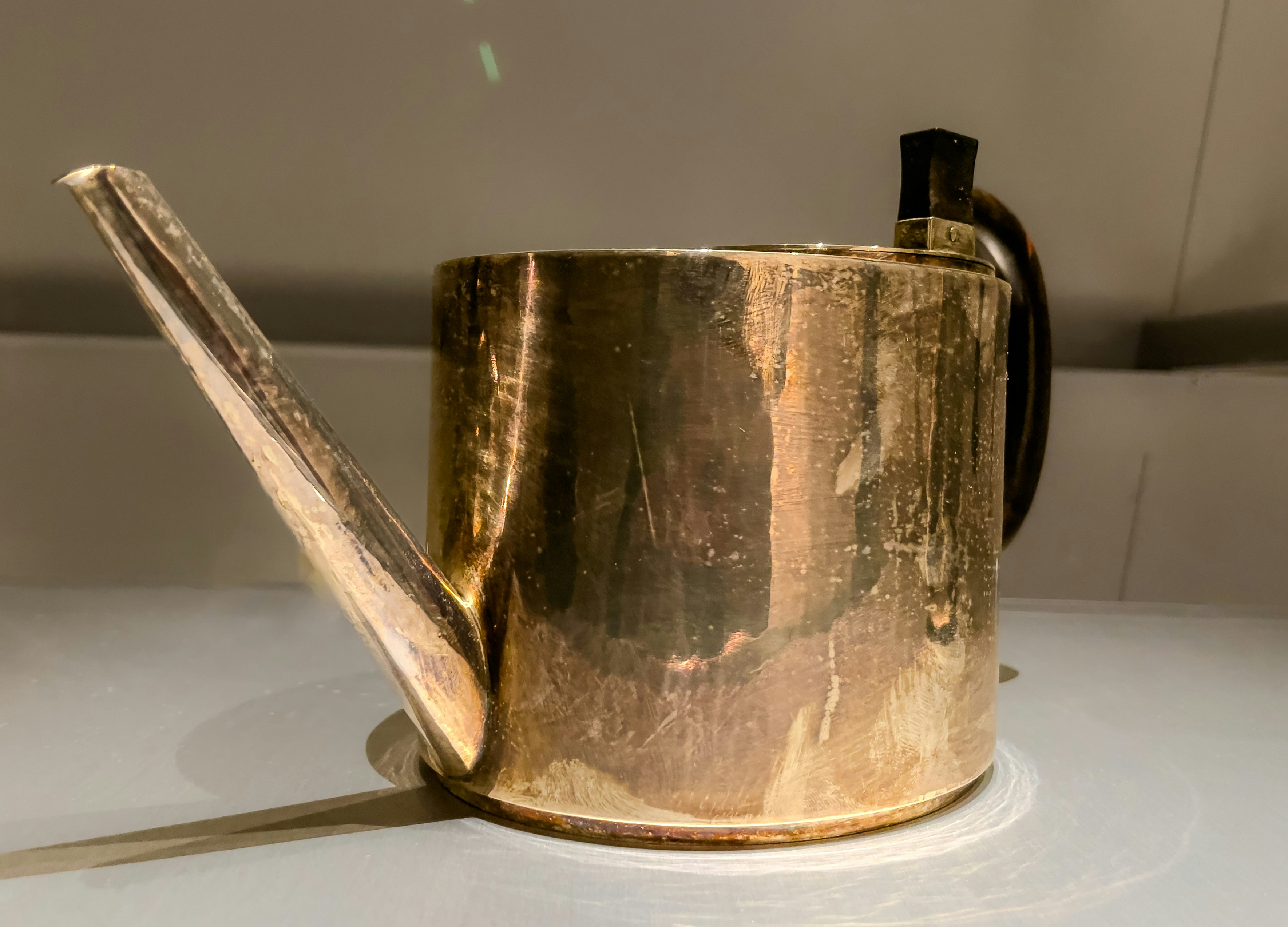 A tarnished brass watering can with a long spout.