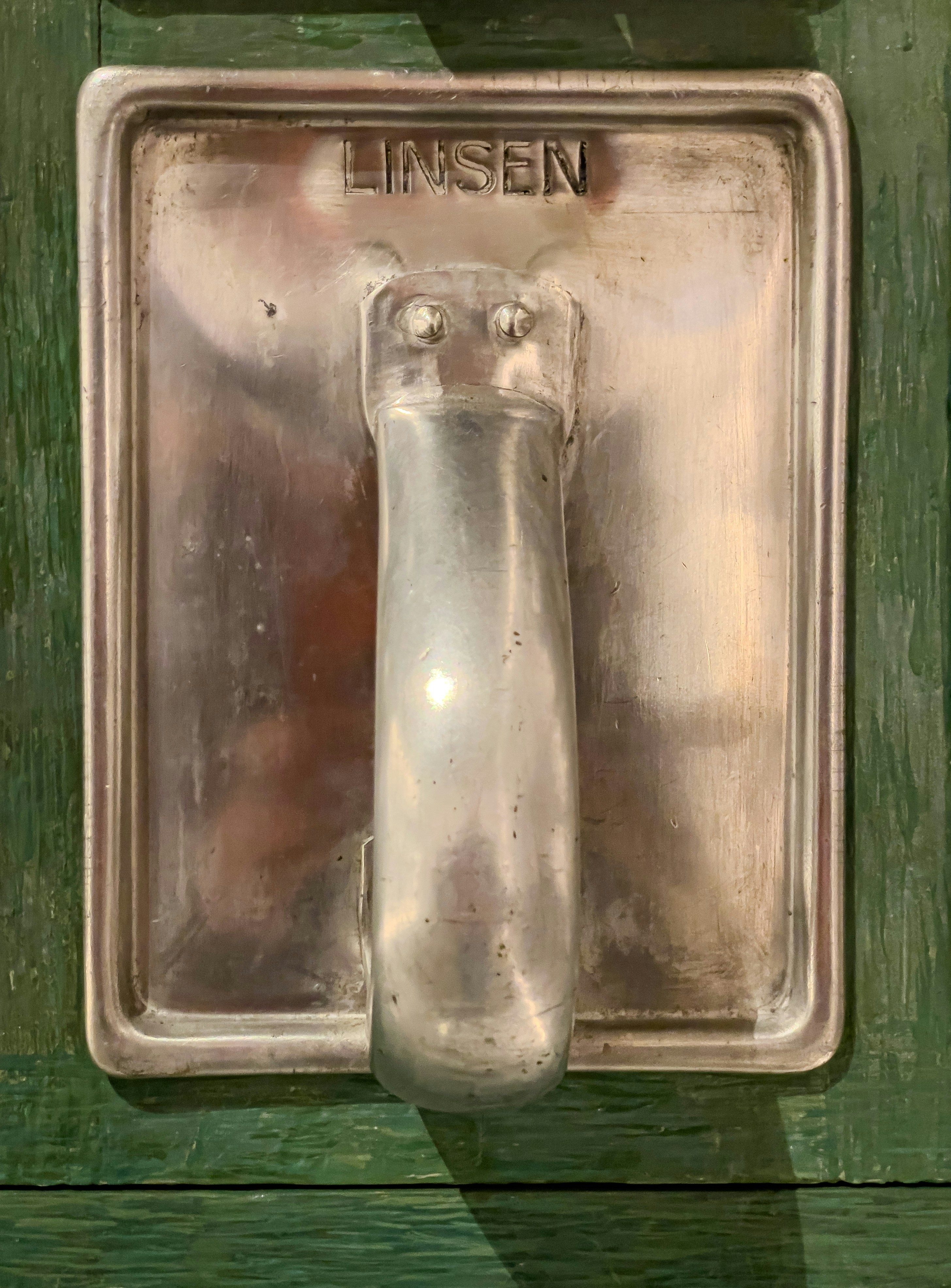 Un aldaboteador de metal vintage con texto "linsen".