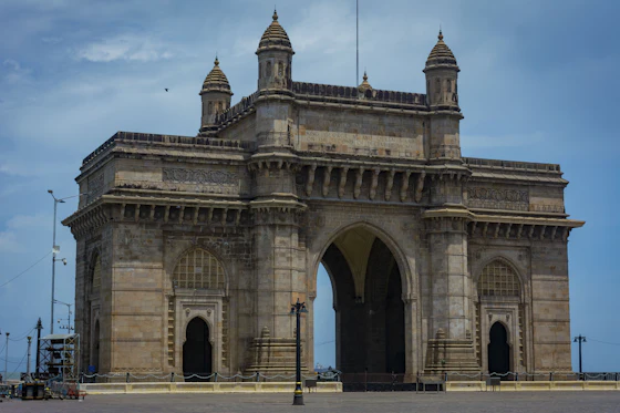 The Gateway of India monument in Mumbai under a cloudy sky