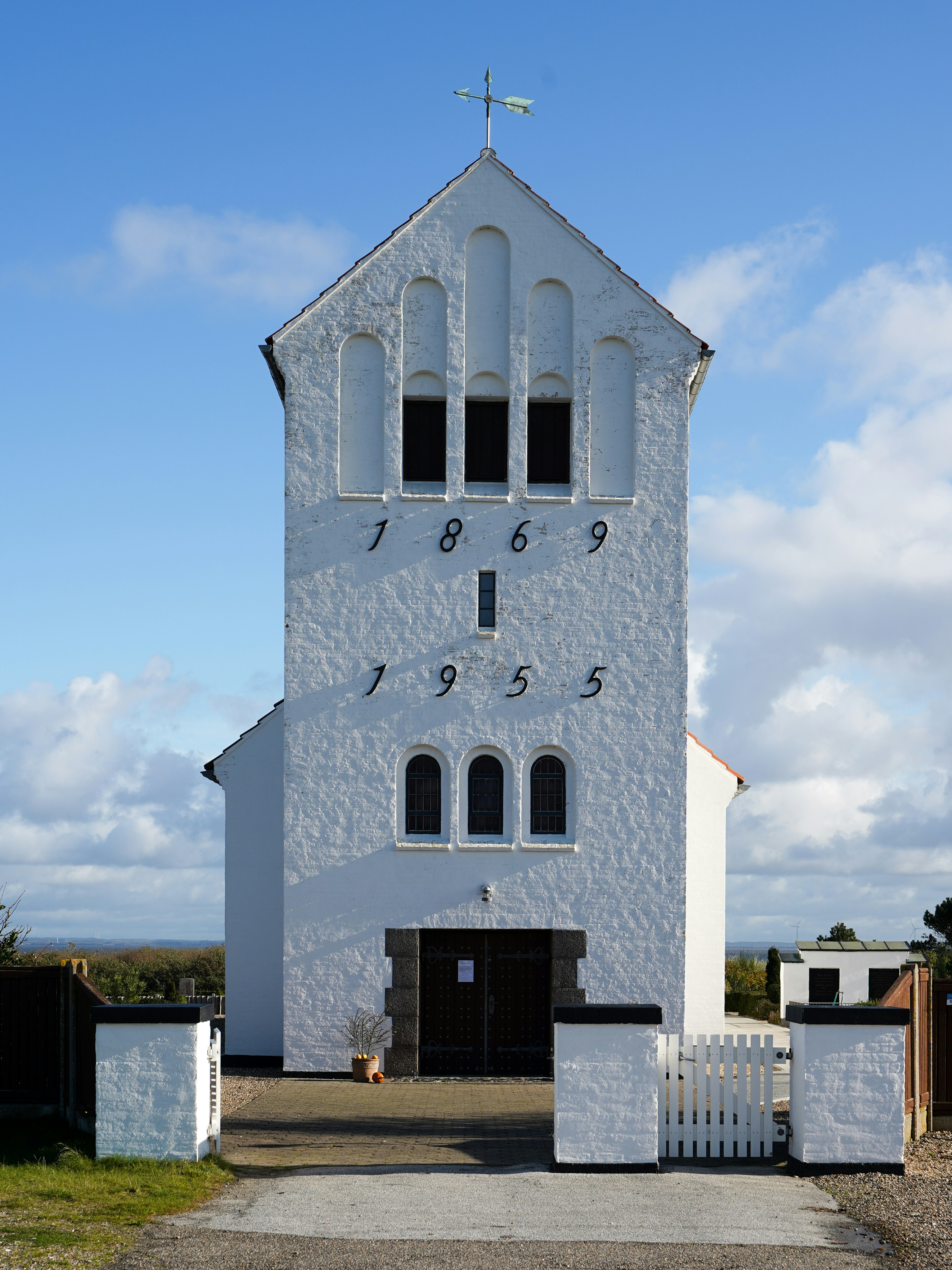 White church tower with arched windows and dates