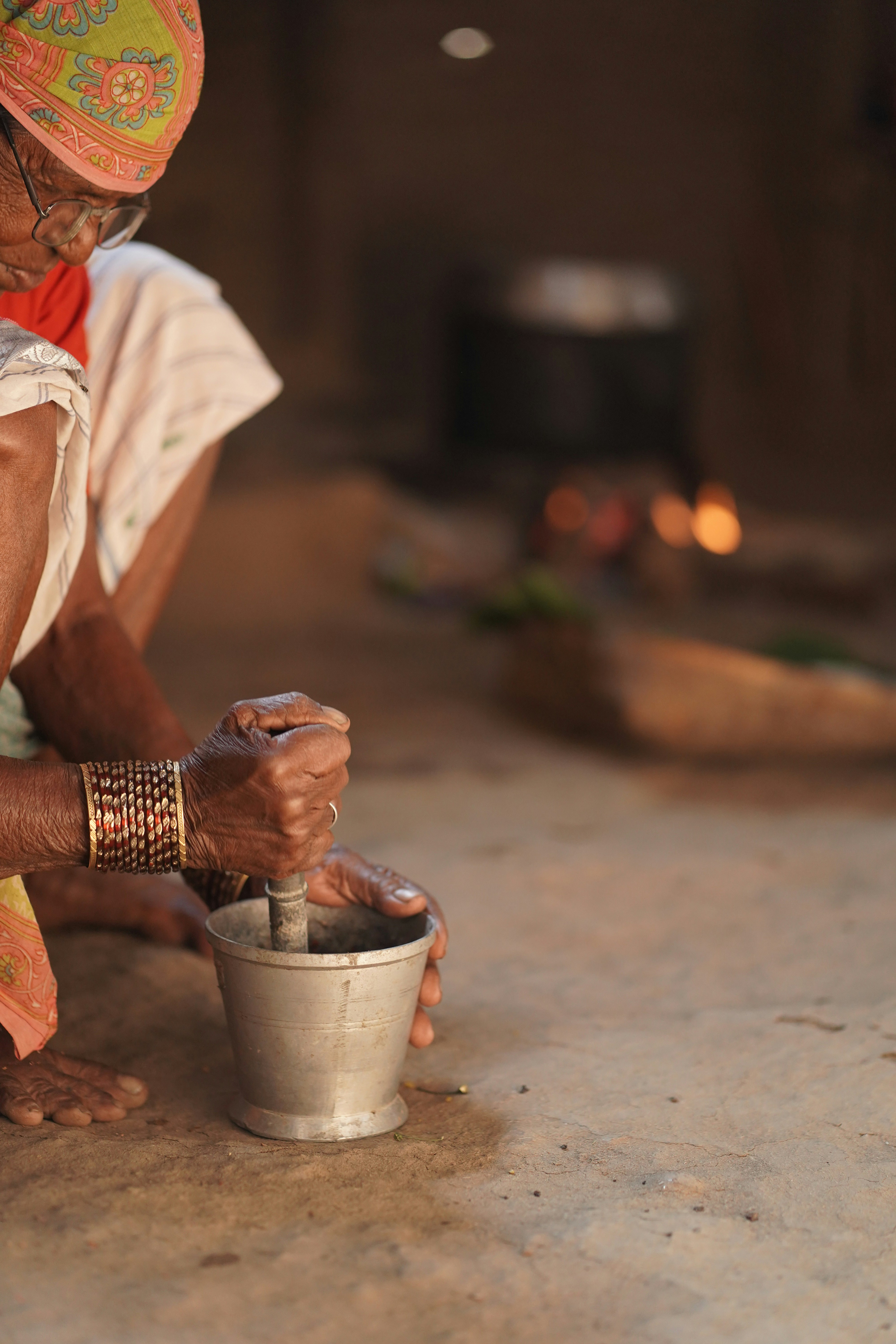 Elderly woman grinding spices in a mortar and pestle.