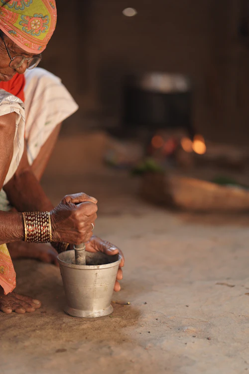 An elderly woman grinding spices at home in India