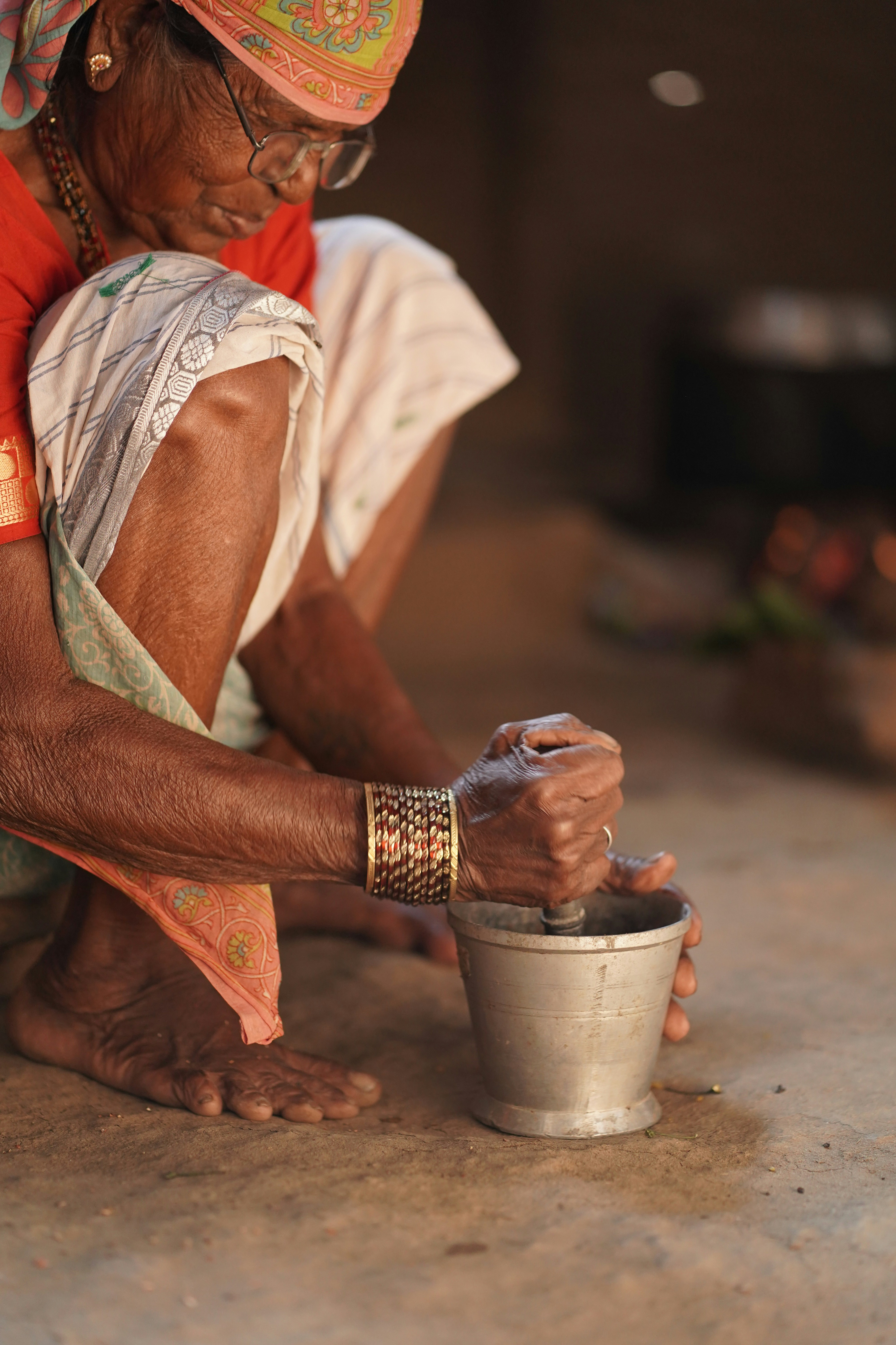 Elderly woman grinding spices in a mortar and pestle.