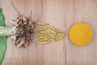 Turmeric root, dried pieces, and powder on a wooden background