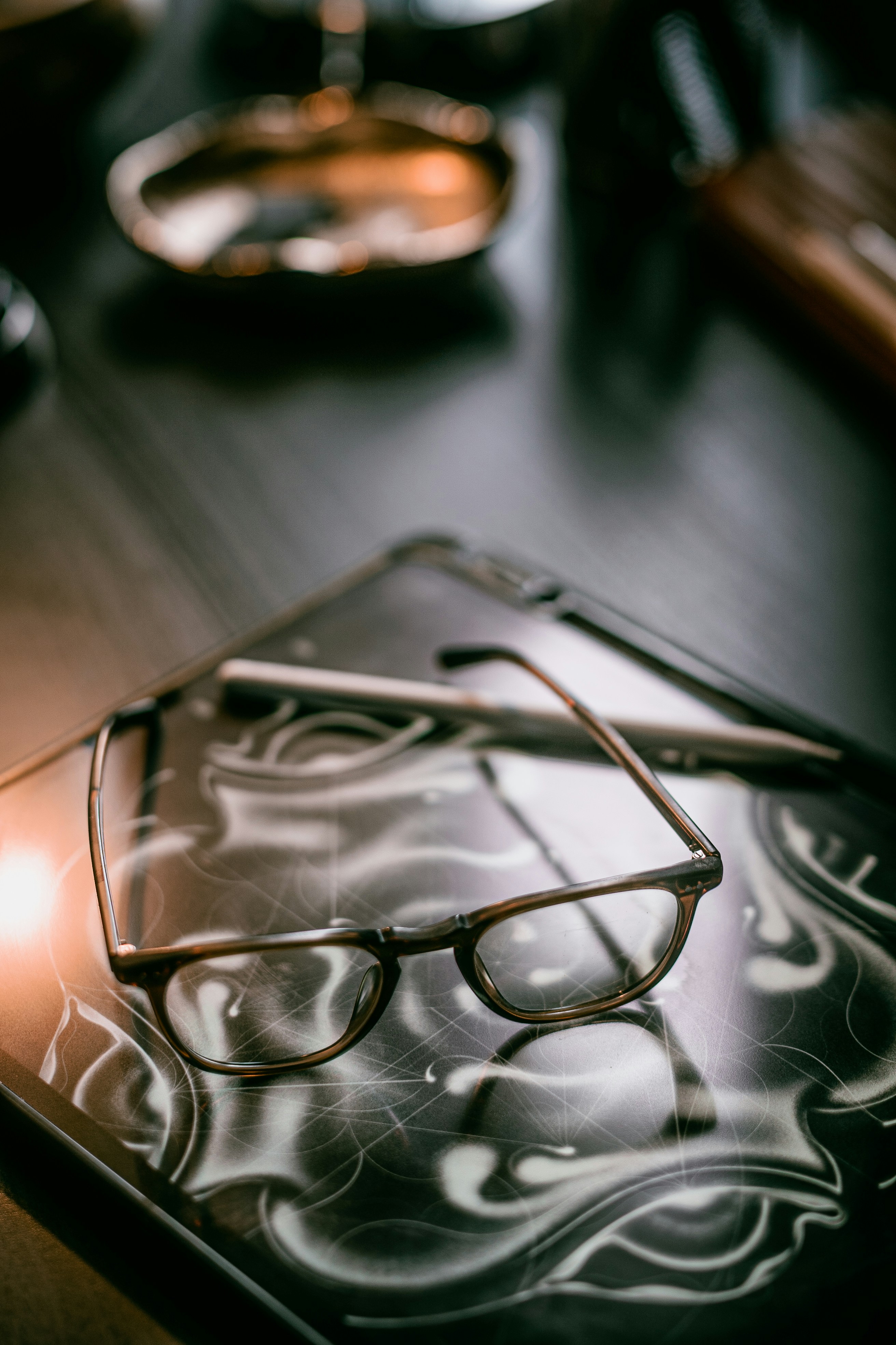 Eyeglasses resting on a tablet with a stylus.