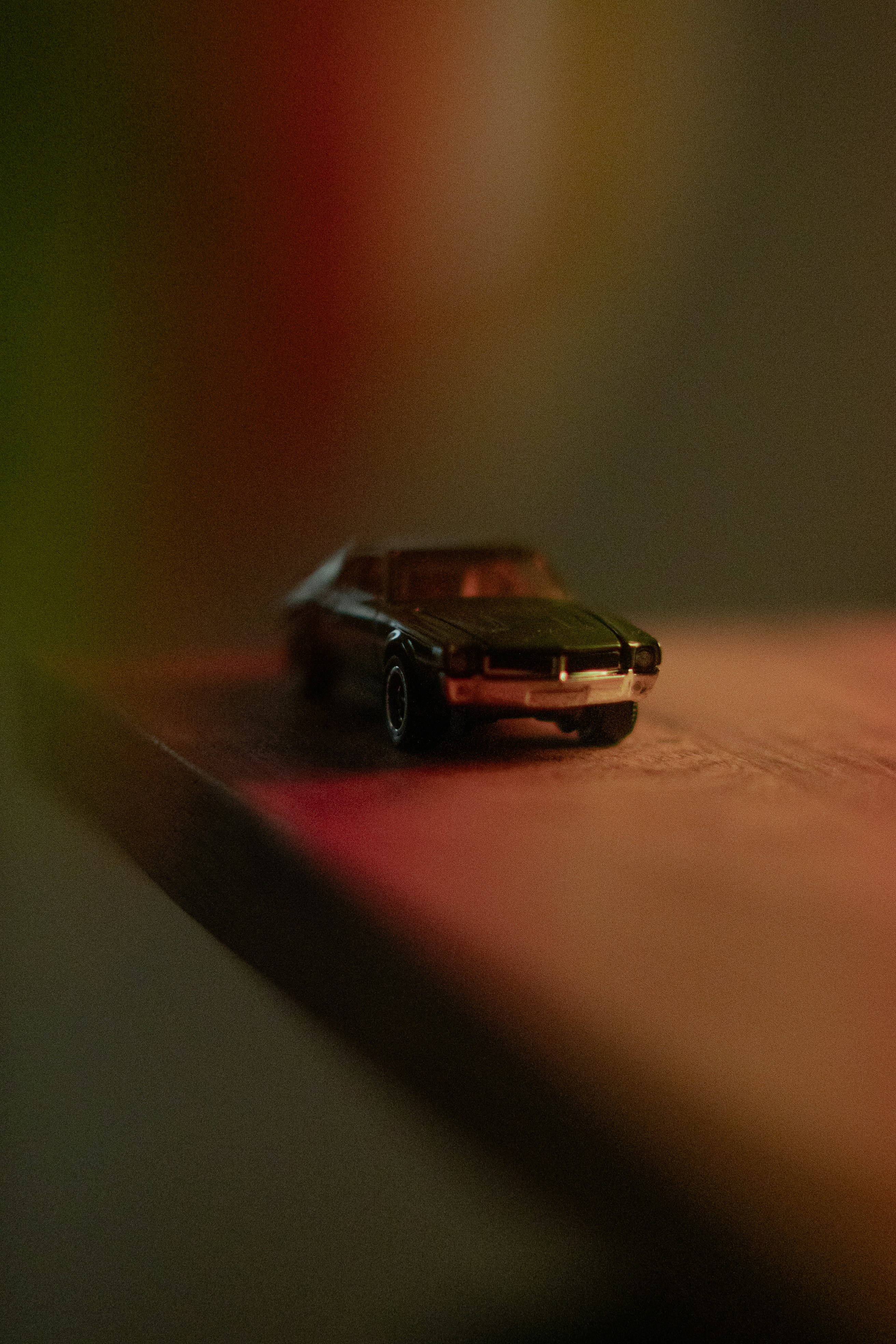 A small toy car sits on a wooden surface.