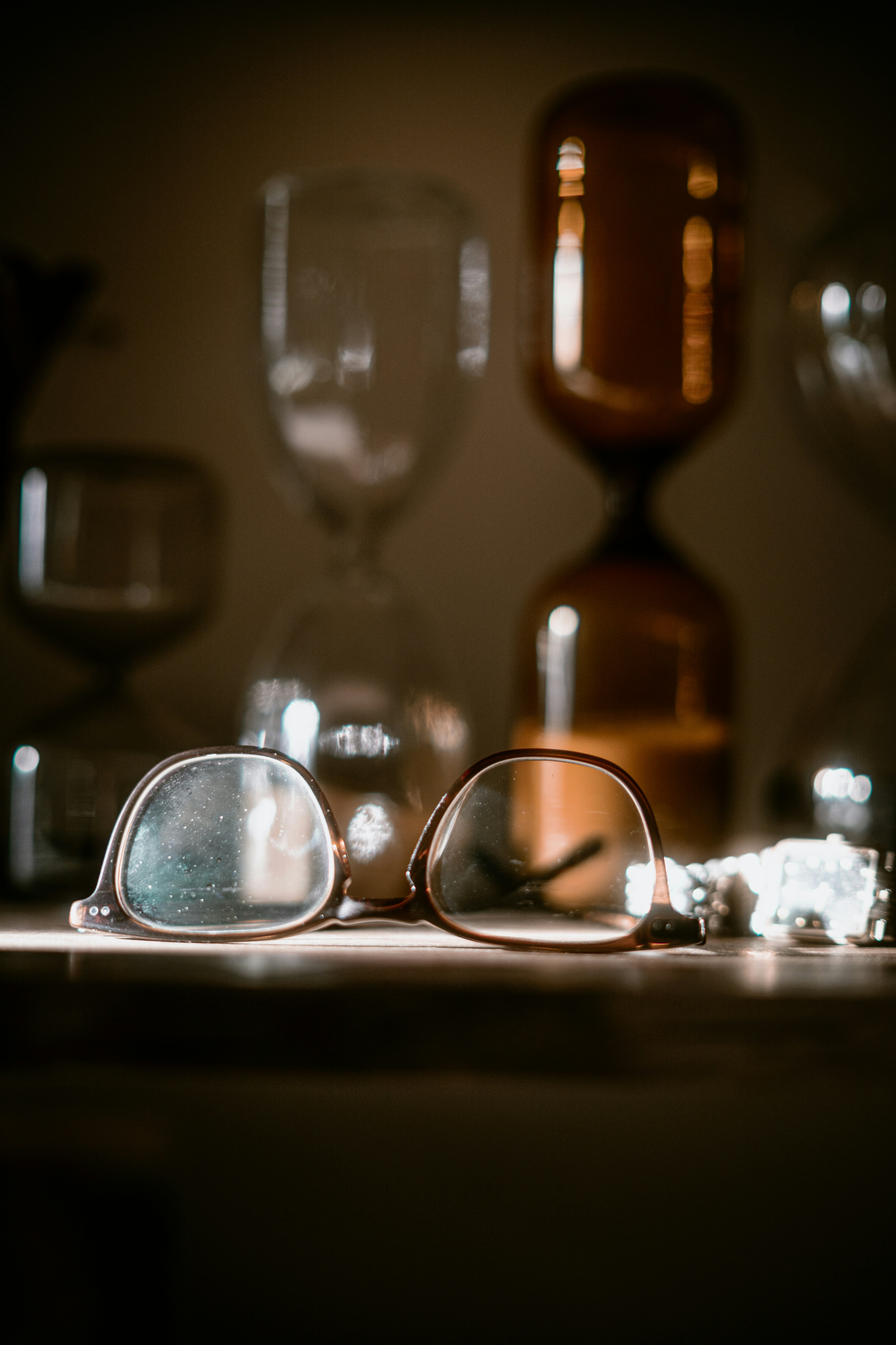 Pair of glasses rests on a shelf with hourglasses.