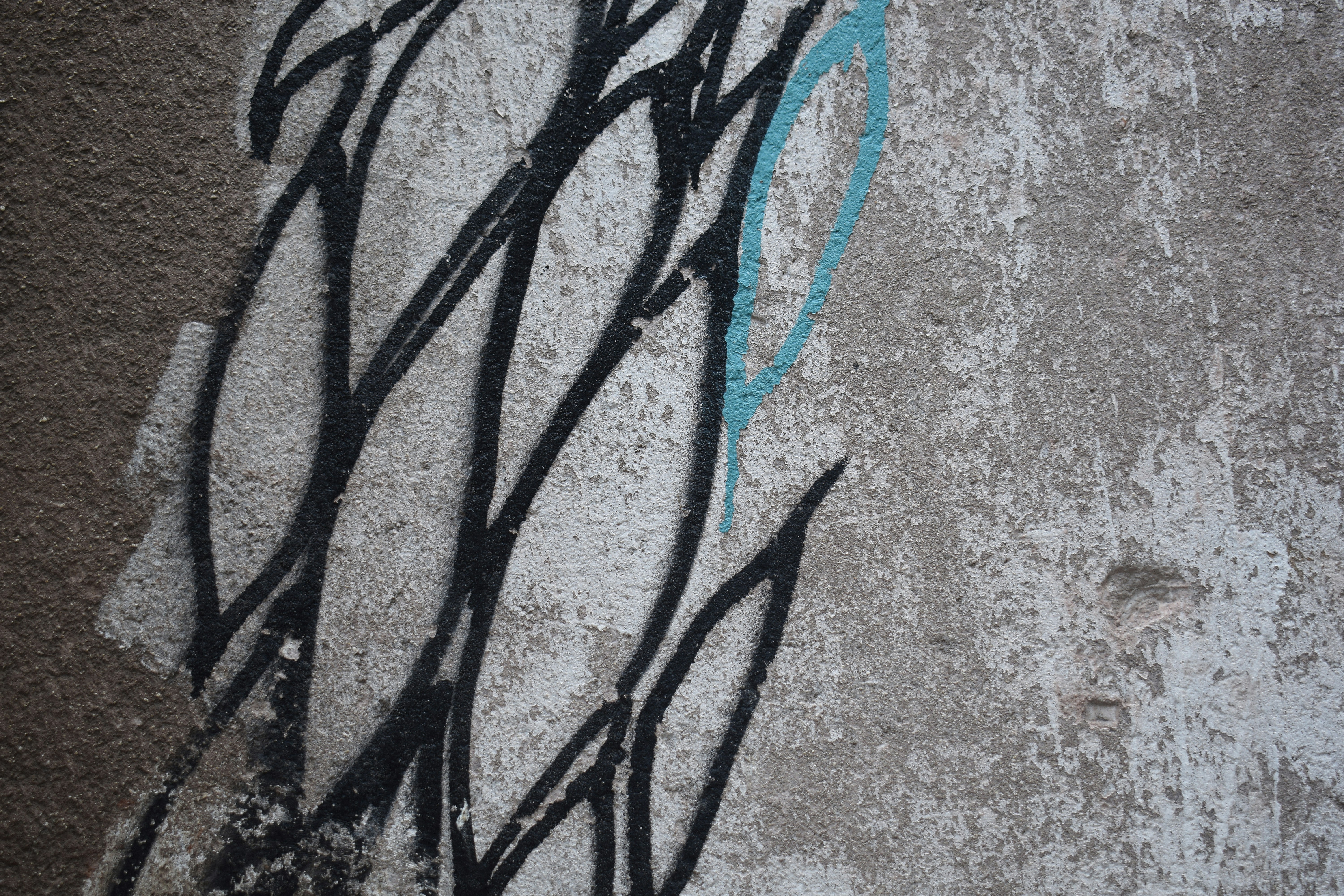 Black graffiti lines on a textured concrete wall