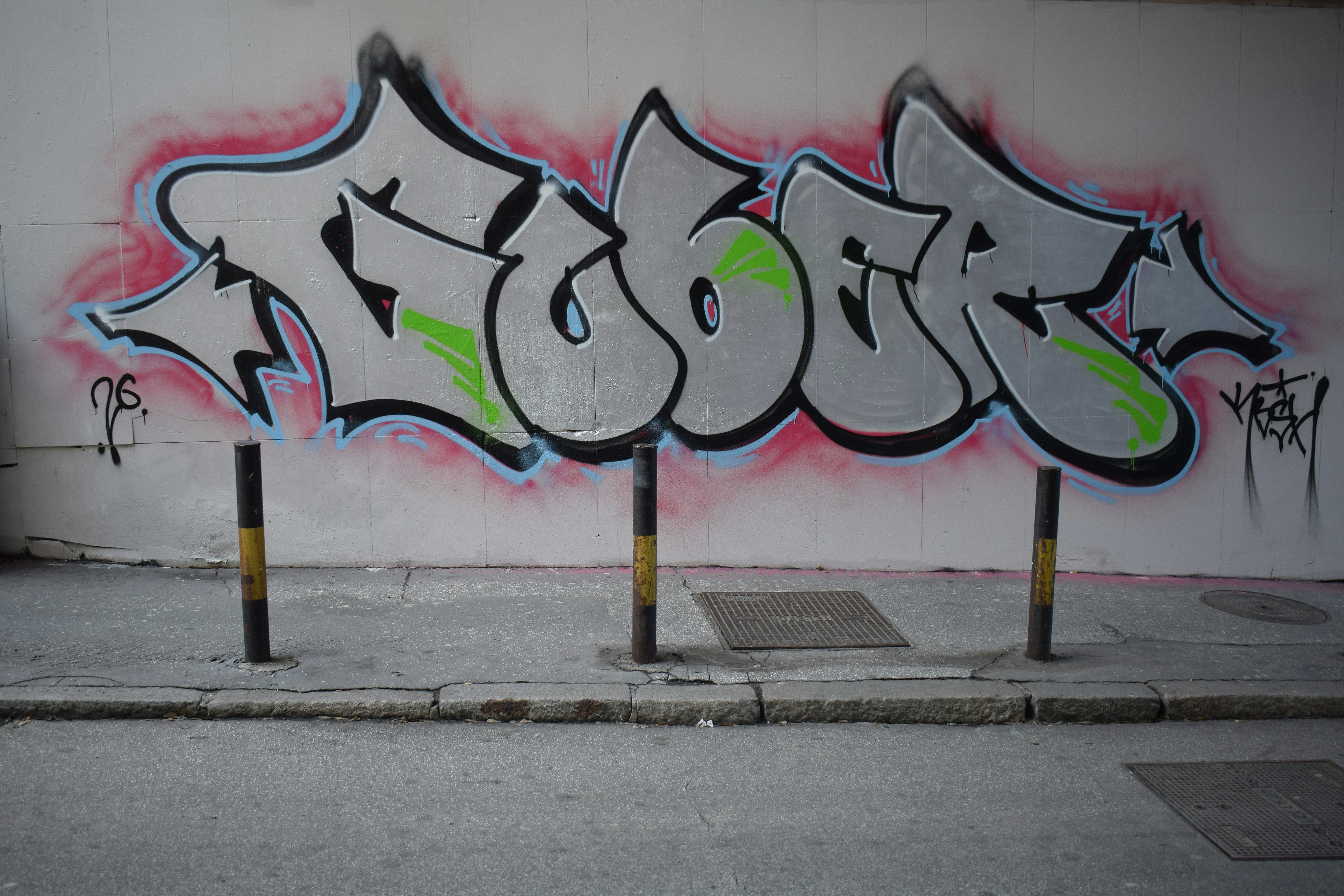 Graffiti art on a concrete wall with bollards.