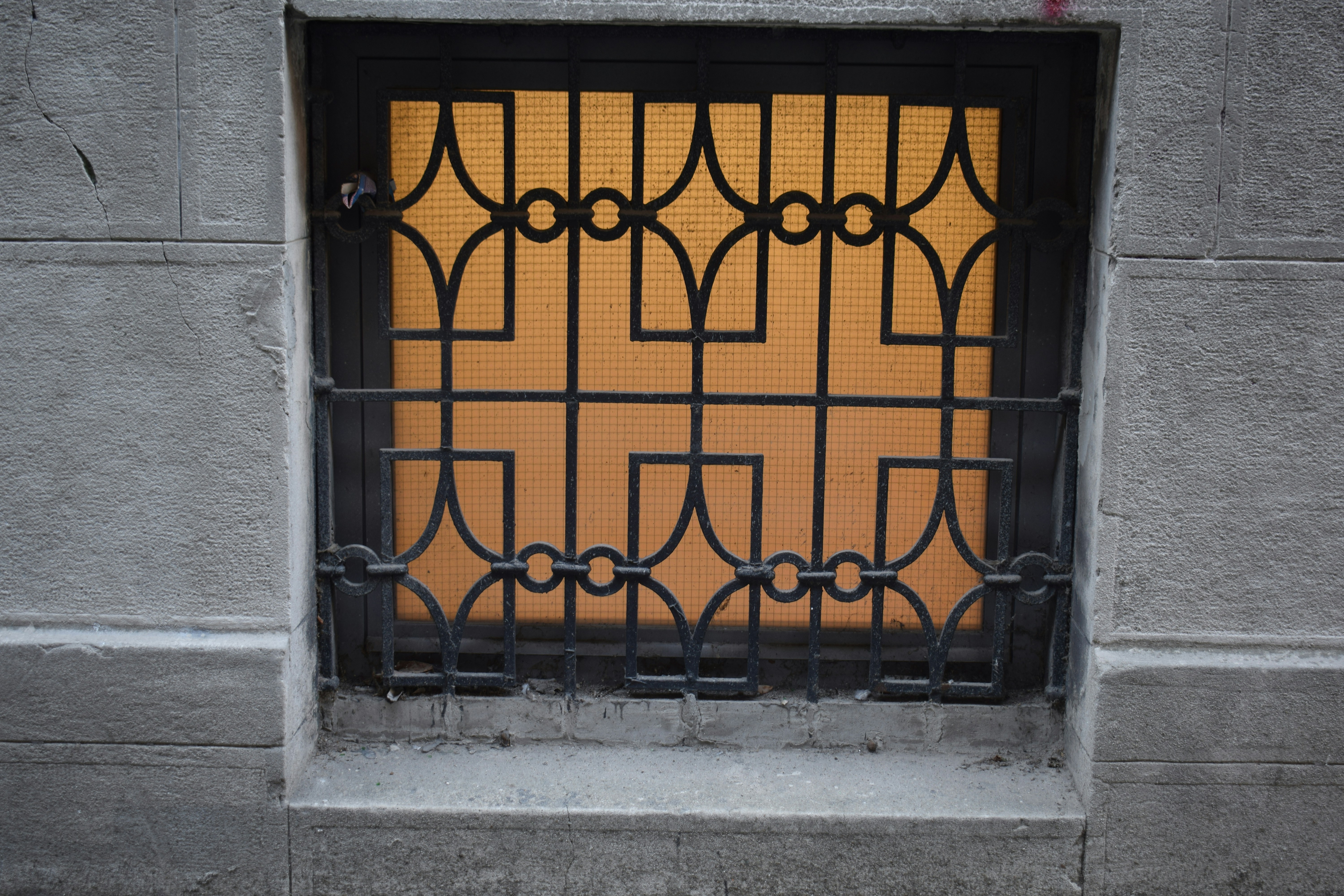 A decorative metal grate covers a window with orange light.