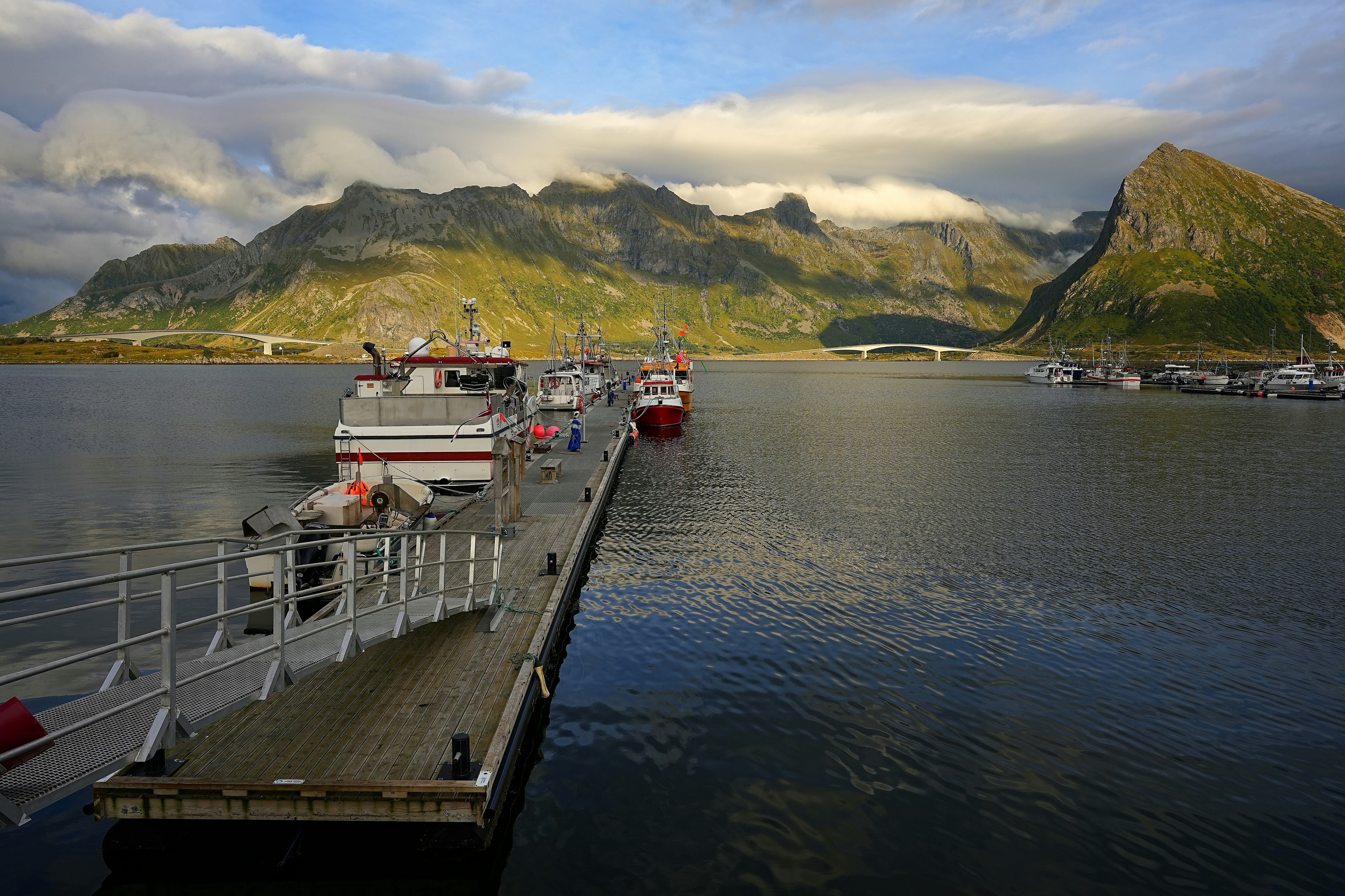 Boats docked at a pier with mountains in the background.