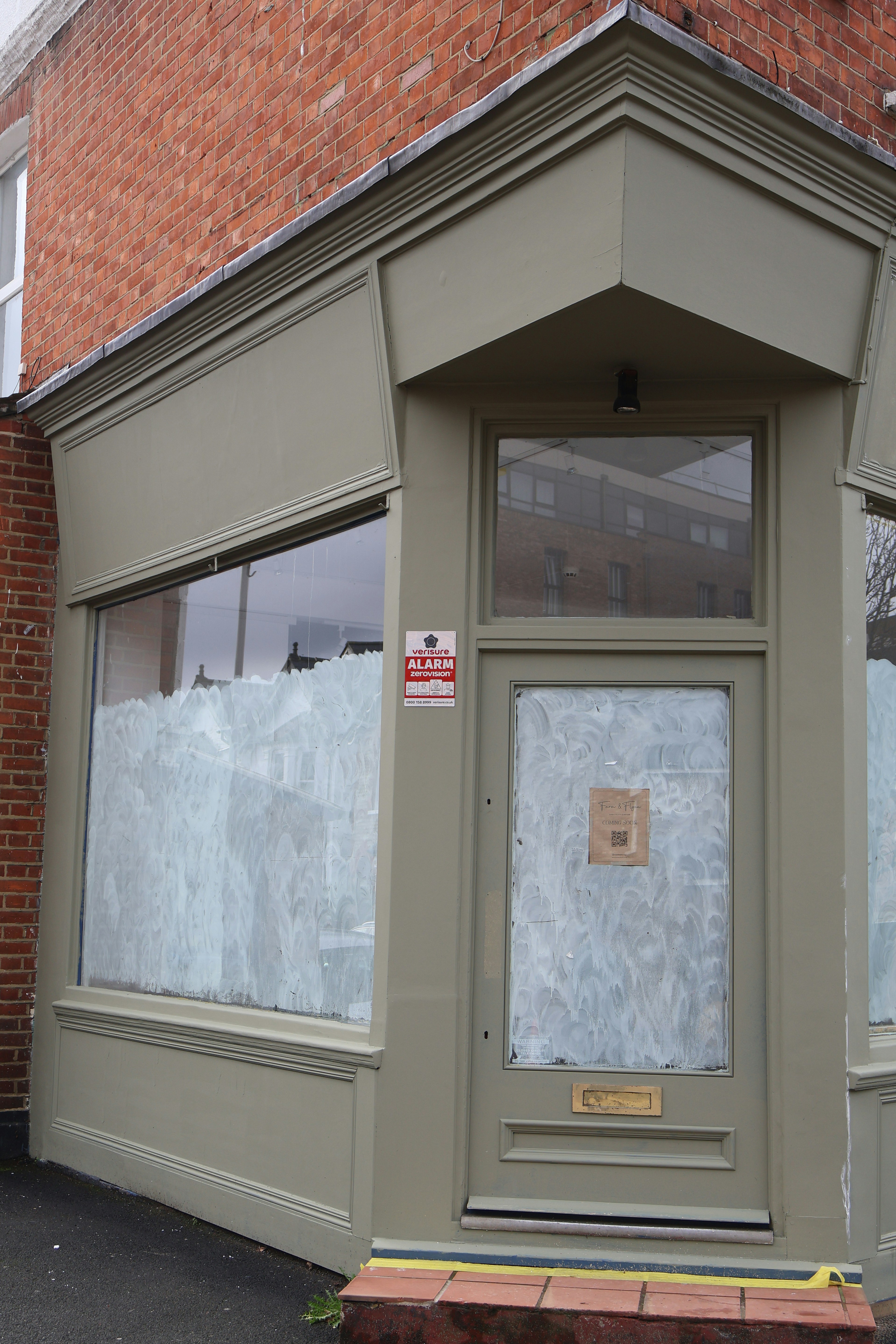 A closed storefront with boarded-up windows and a door.