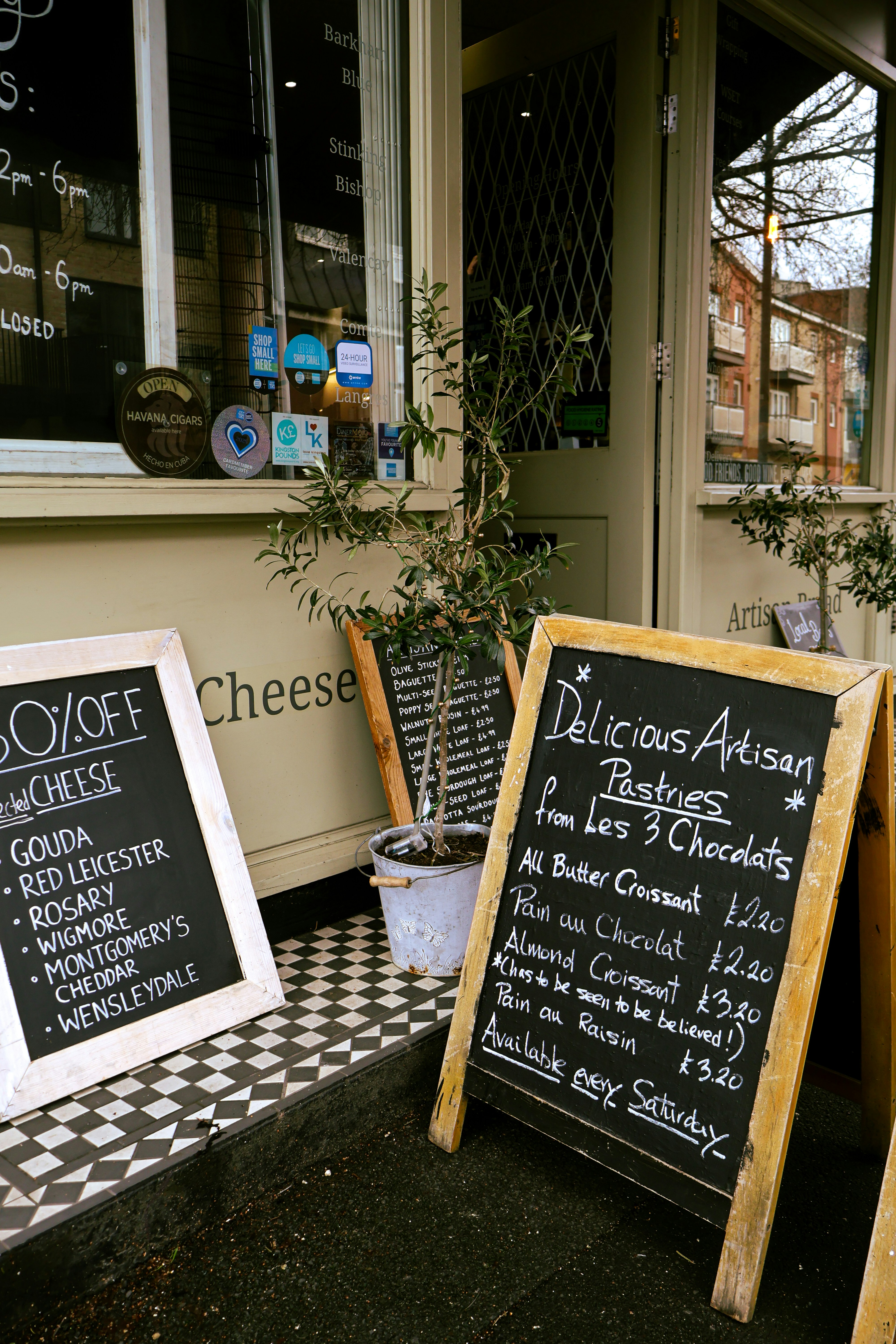 Kreidetafel-Menüs vor einer Käse- und Konditorei.