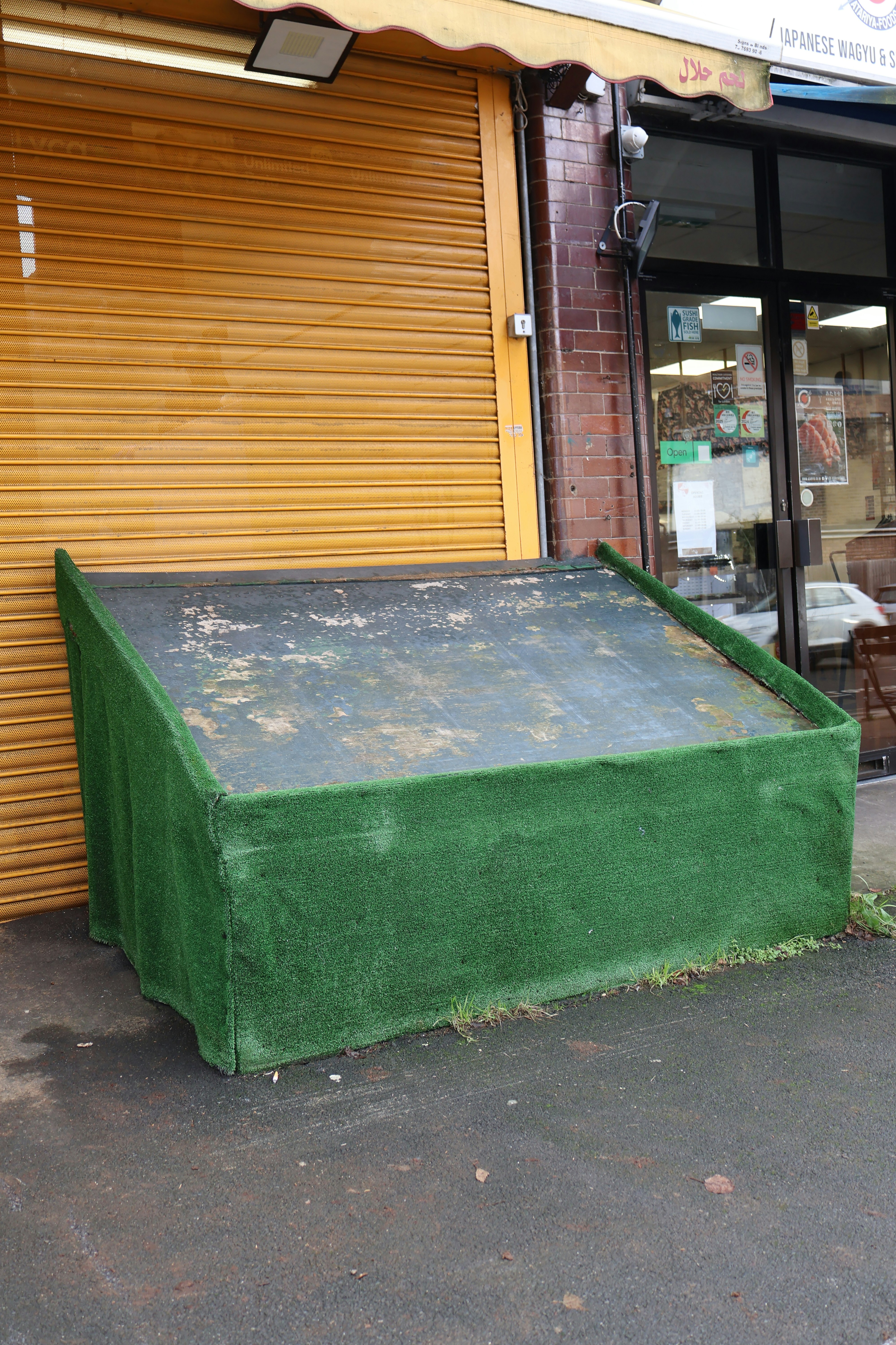 Un expositor cubierto de verde frente a una tienda.