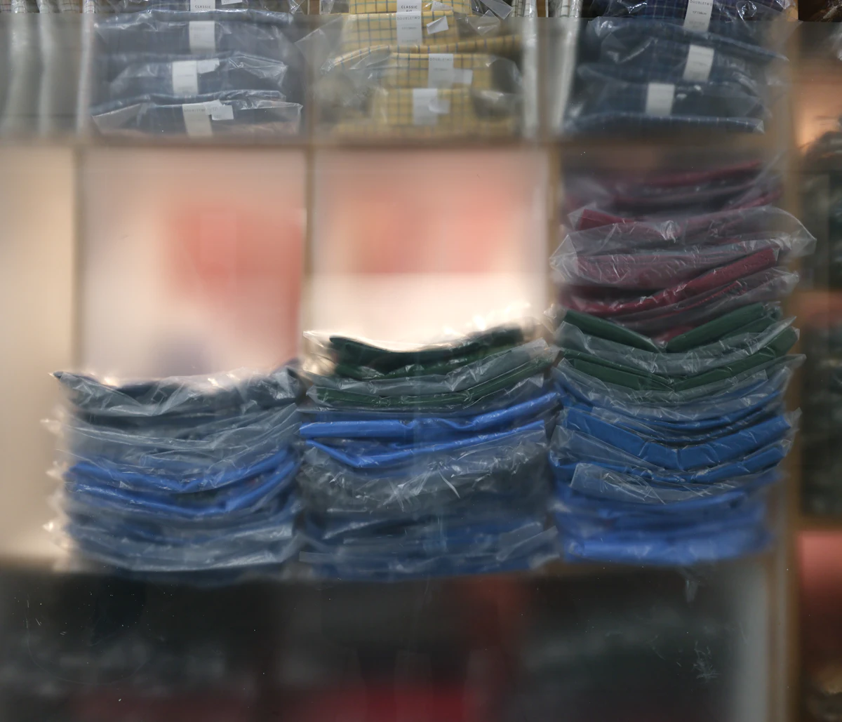 Tumpukan kain dan pakaian terlipat yang sudah dikelompokkan dan dibungkus plastik bening