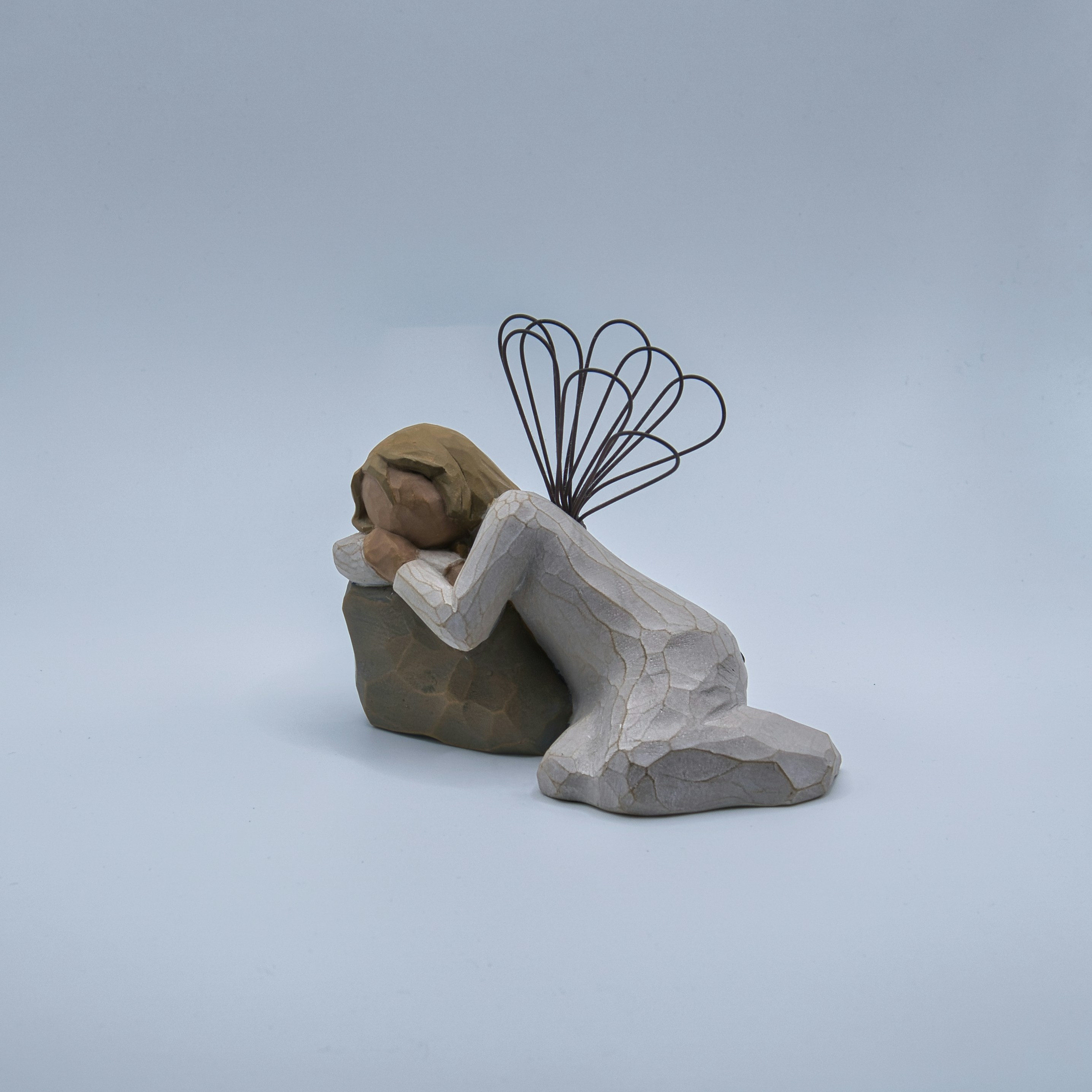 Angel figurine resting head on a rock