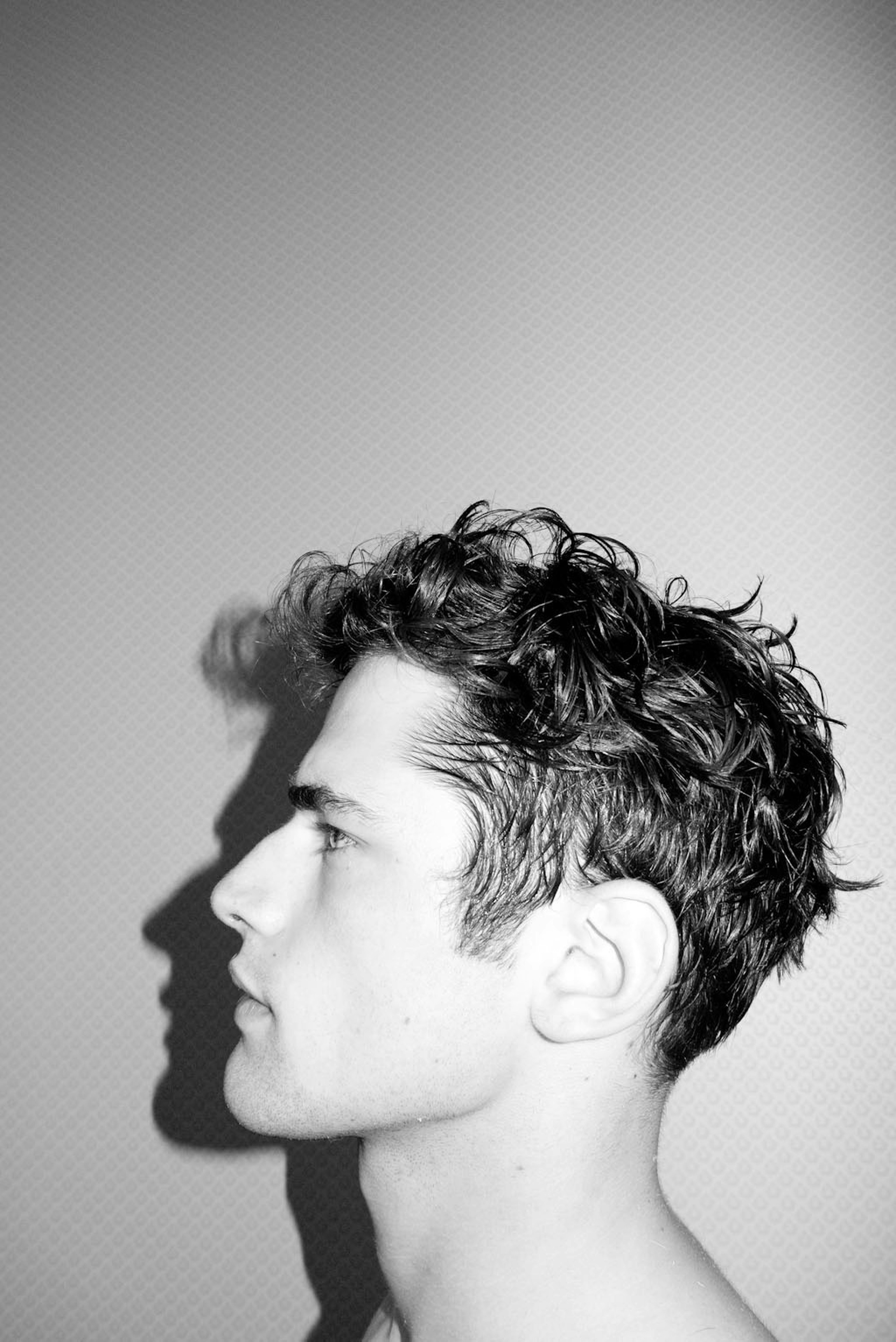 Perfil de un joven con pelo rizado.