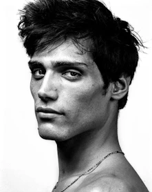 A man with dark, messy hair and a serious expression