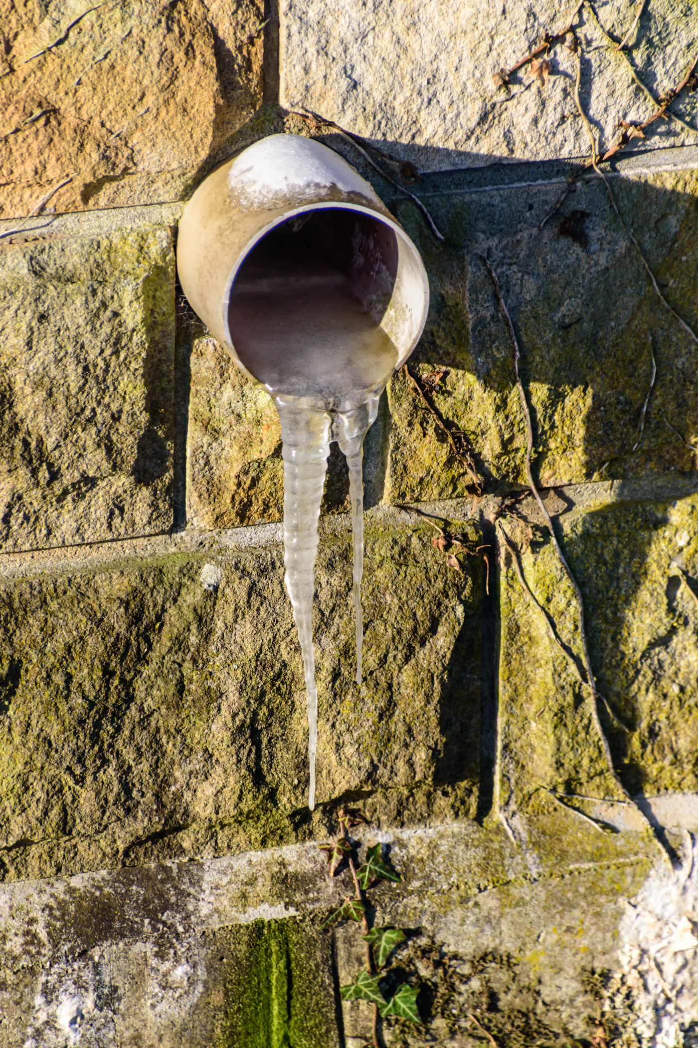Frozen pipe with long icicles in cold weather