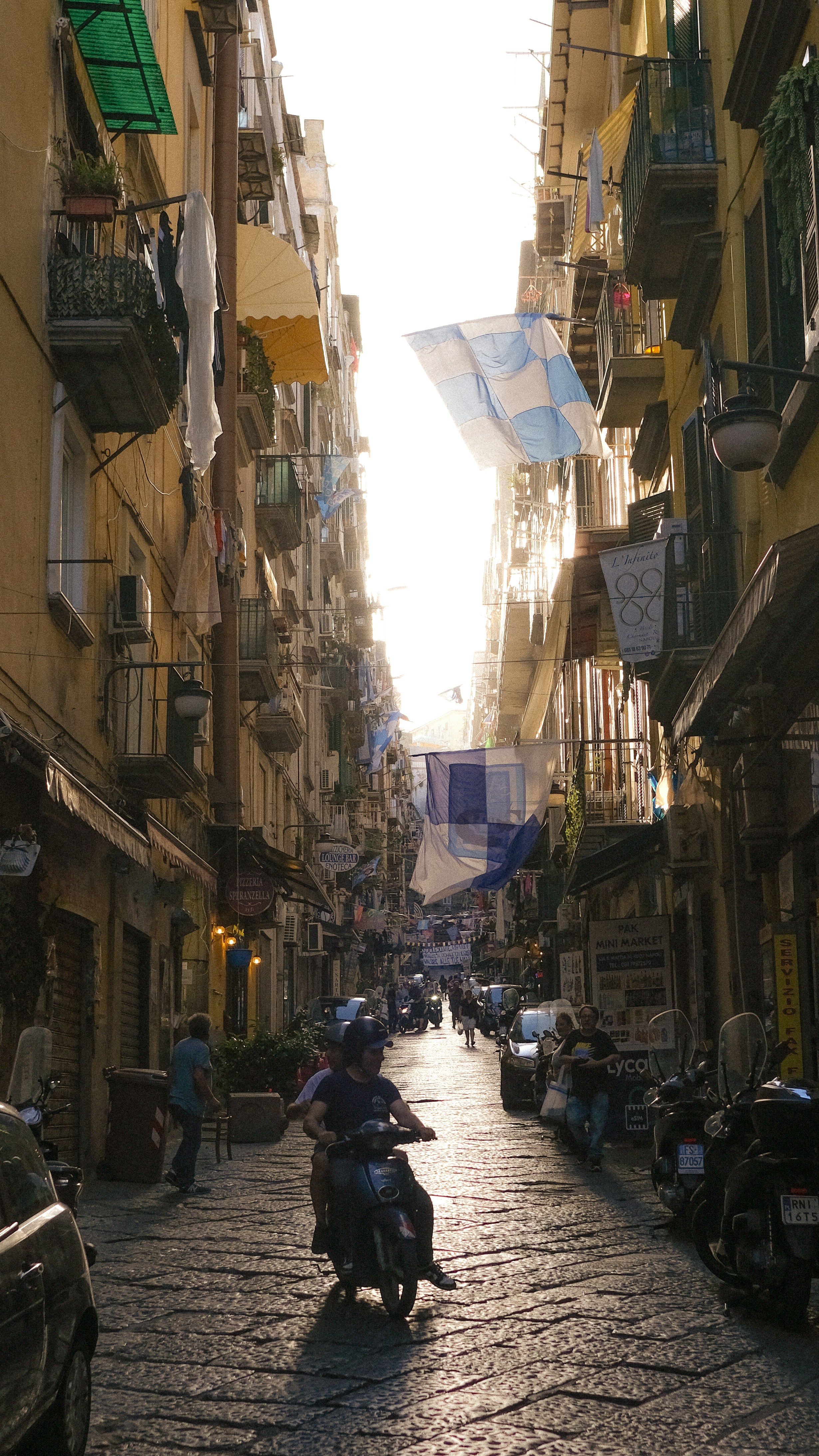 旗を掲げた狭い通りを走るスクーター。