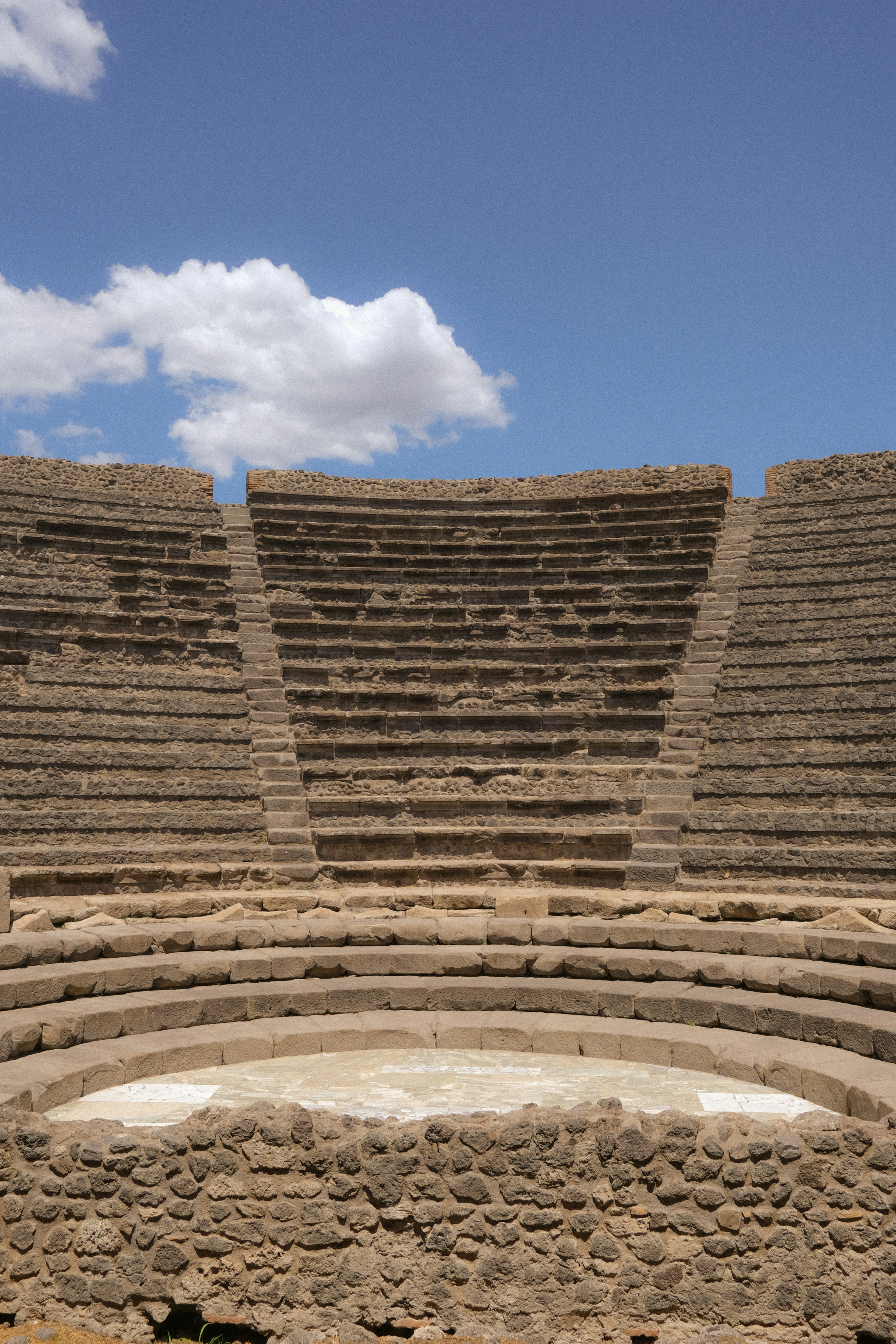 青空の下、座席のある古代の石造円形劇場