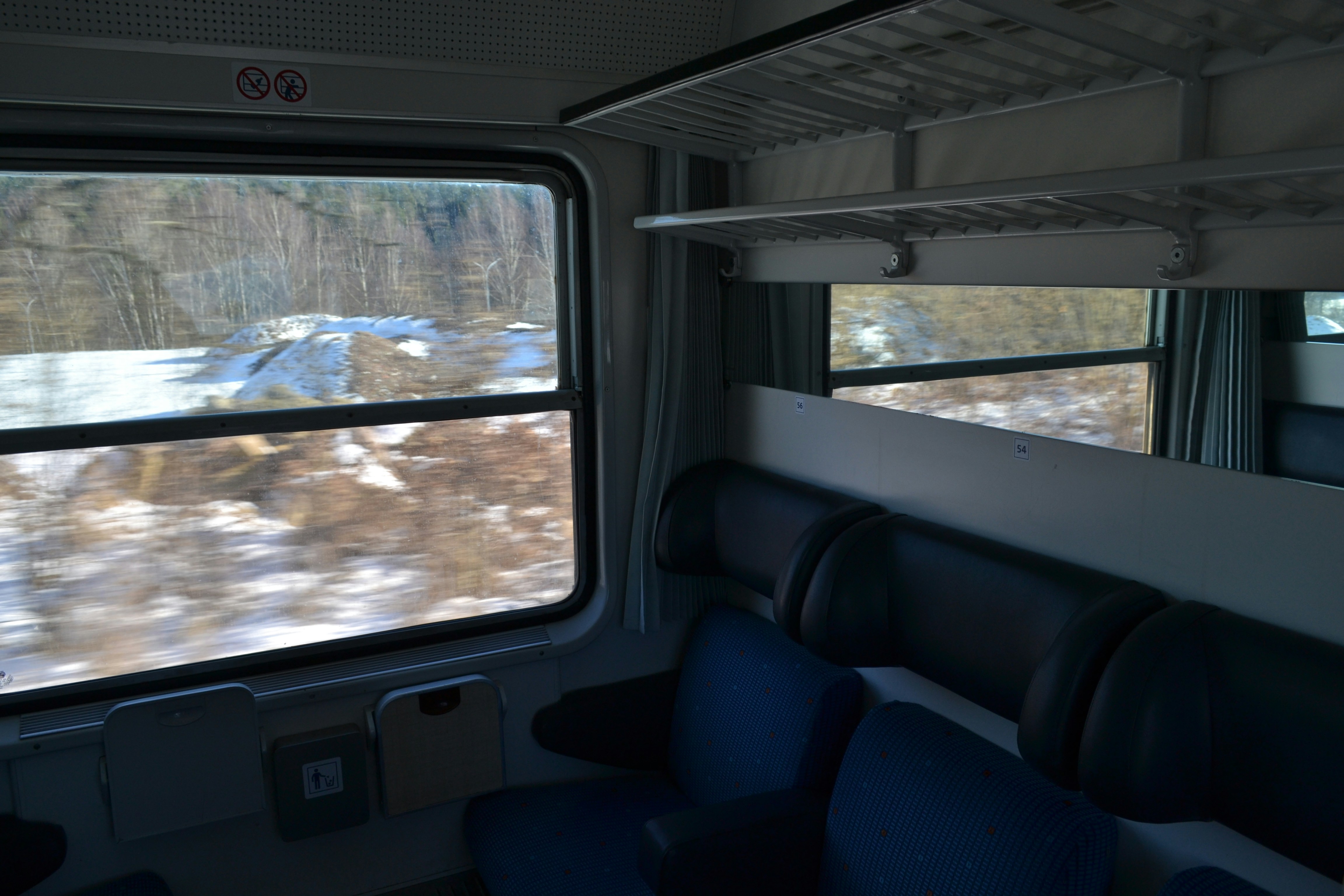 Vista interna di un treno con paesaggio innevato all'esterno.