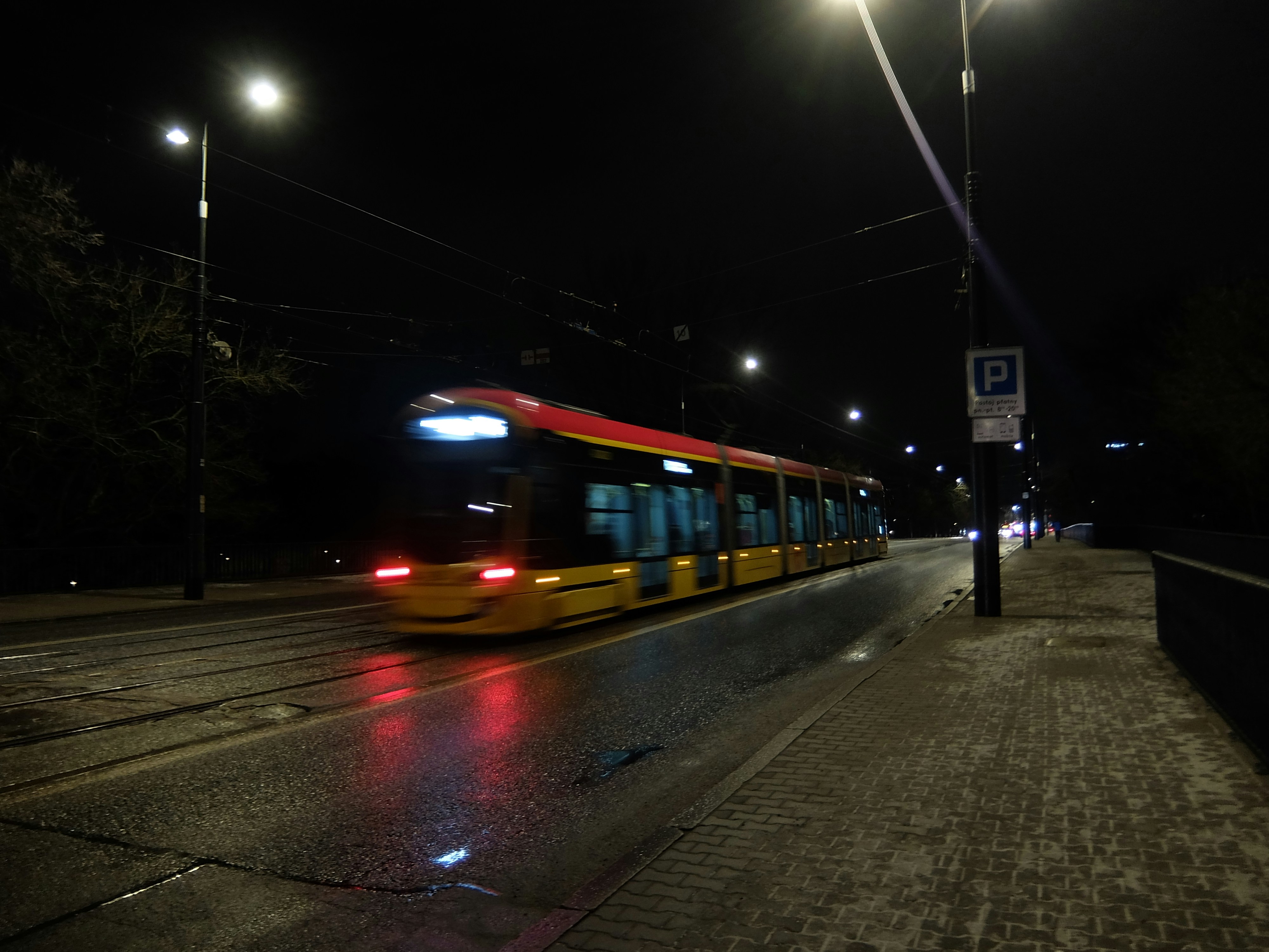A tram moves through a city at night.