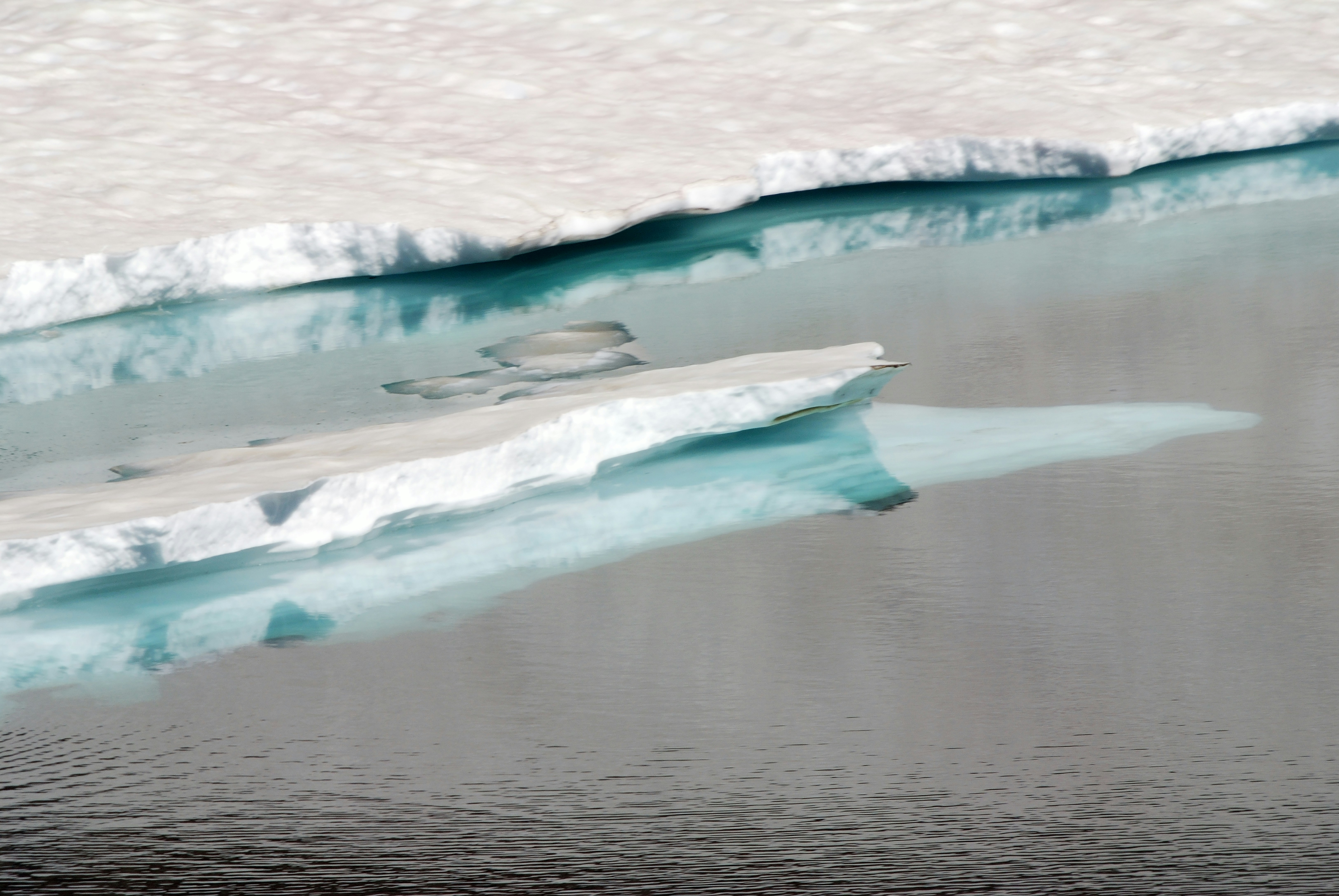 Iceberg floating in blue water with reflection