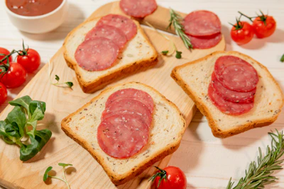 Slices of salami on toast with tomatoes and herbs
