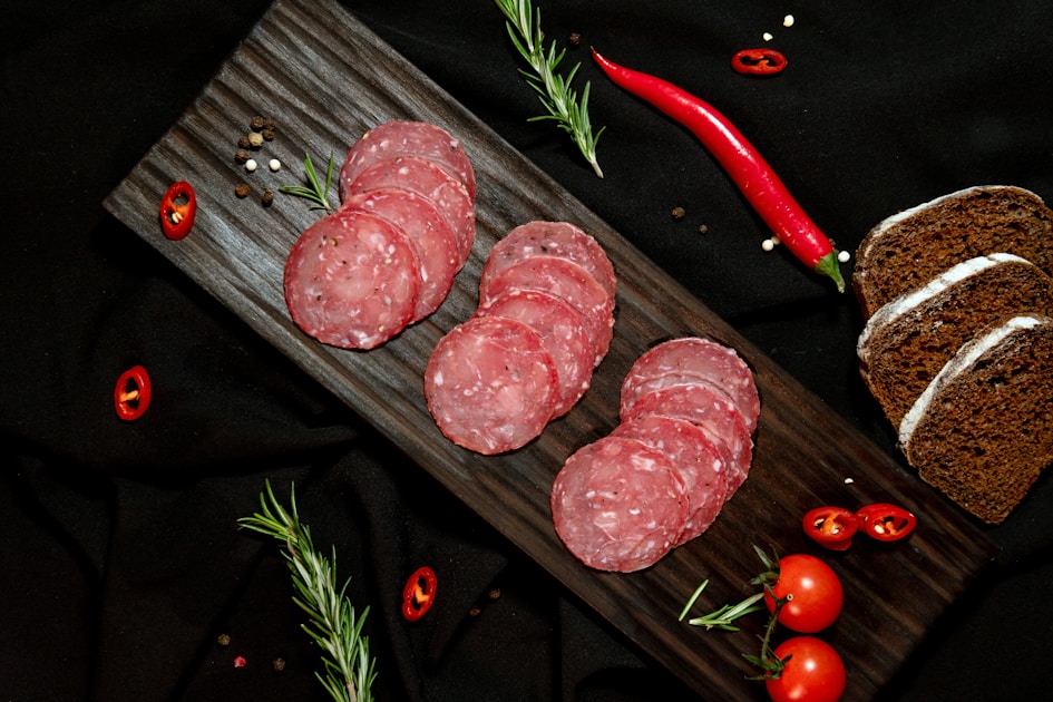 Salami calabrais épicé tranché avec piment rouge et pain sur planche