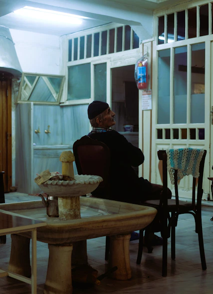 Elderly man sitting in a dimly lit room.