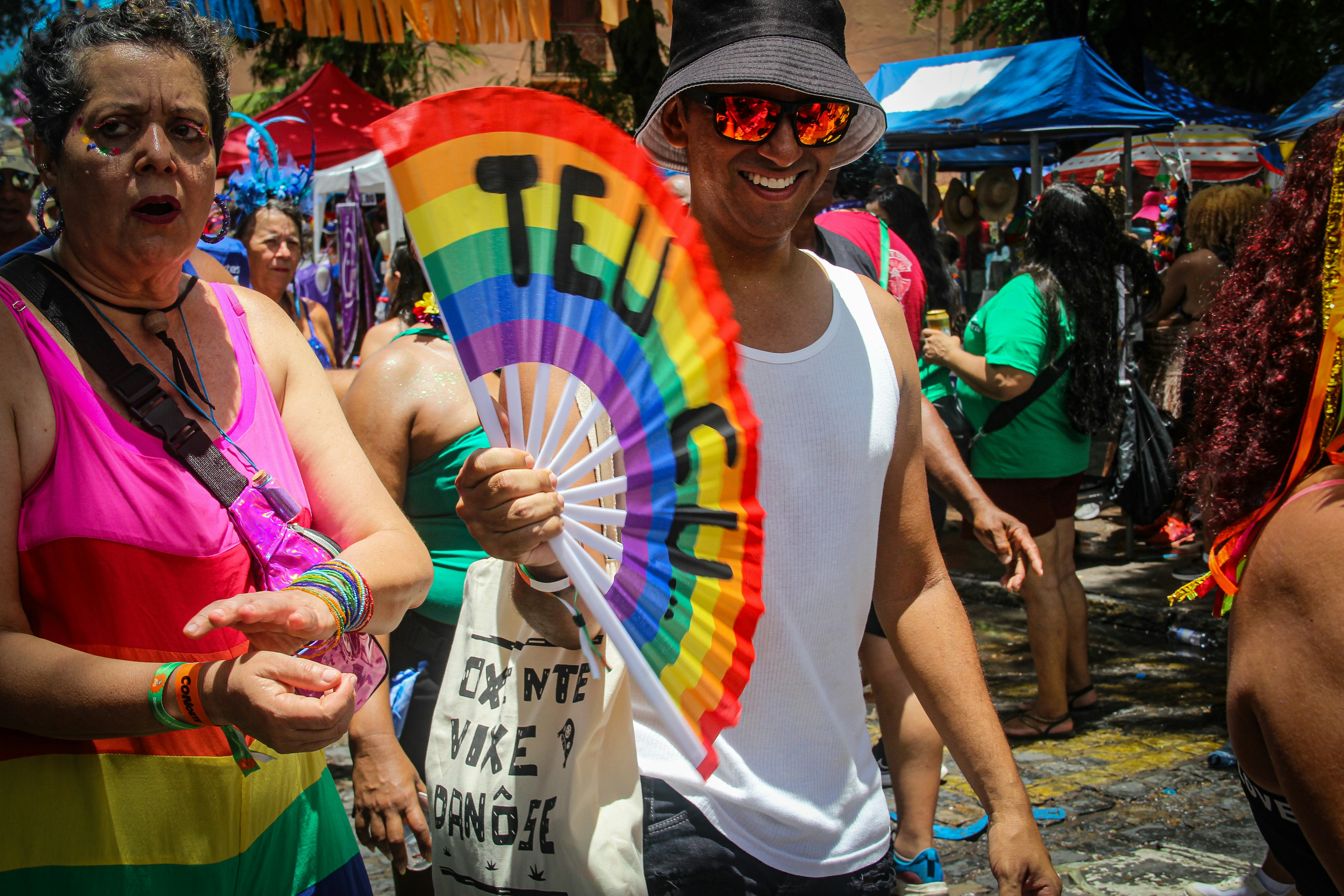 Man holds rainbow fan at a pride parade