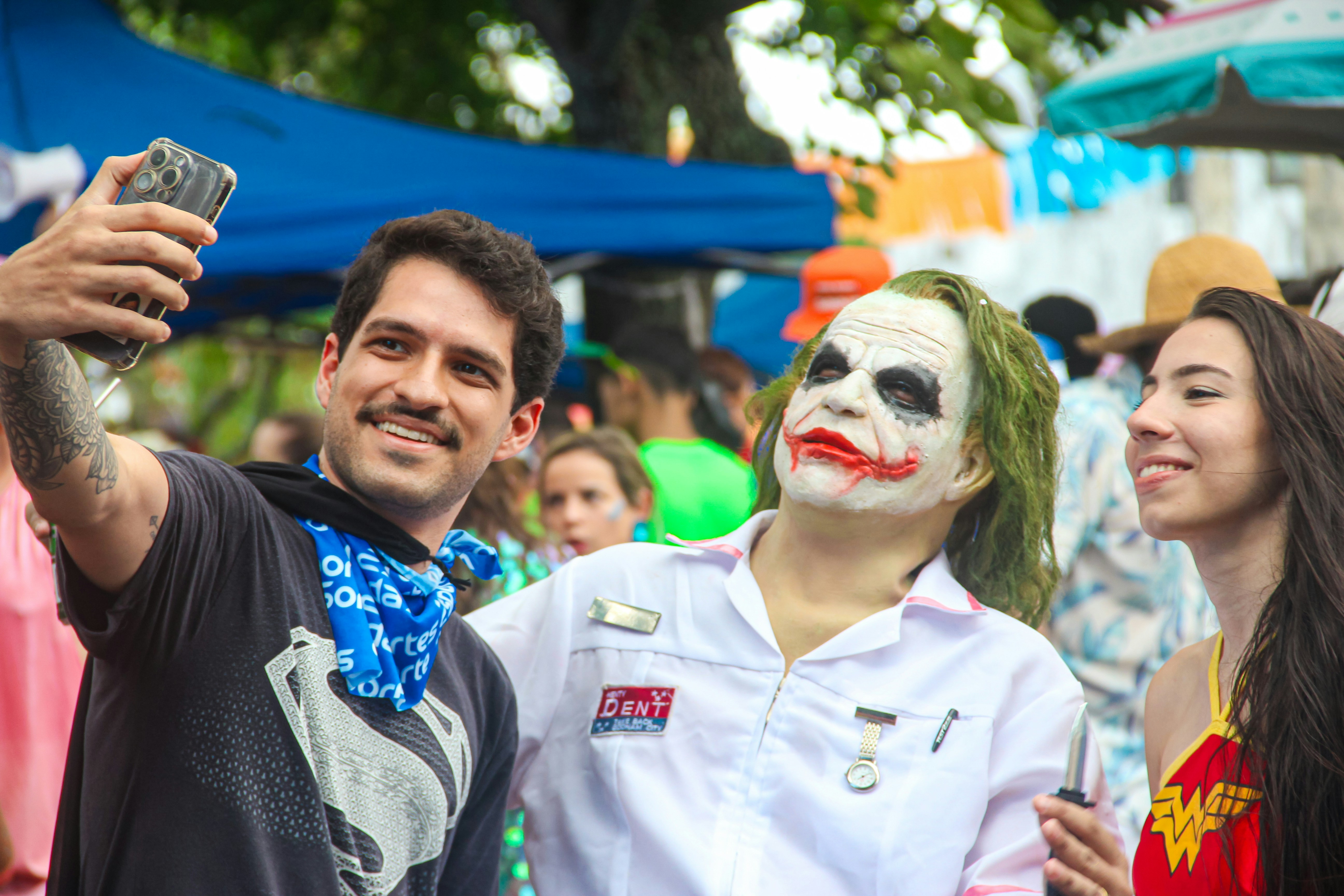 Man in joker costume takes a selfie with friends.