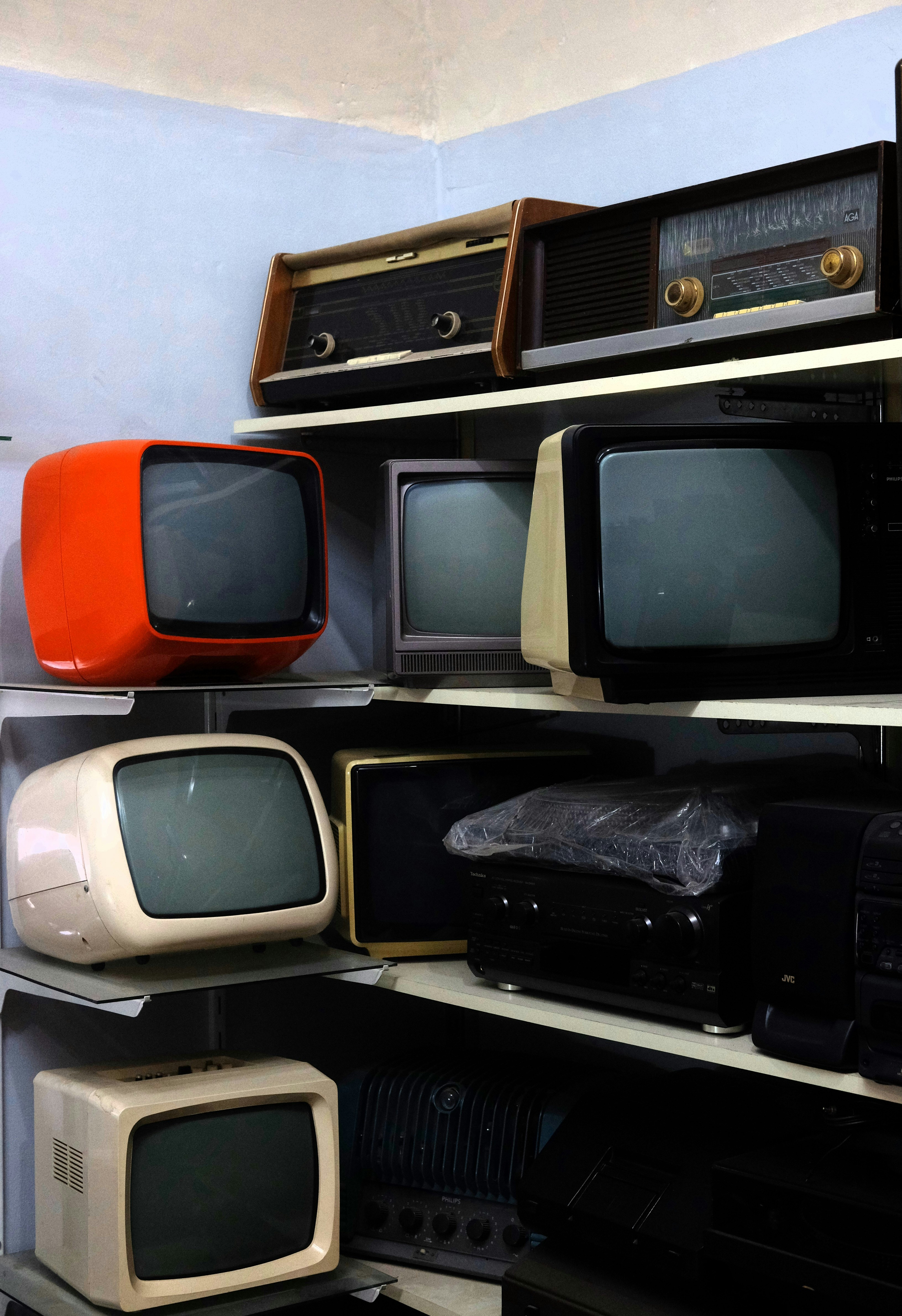 Collection of vintage televisions and radios on shelves