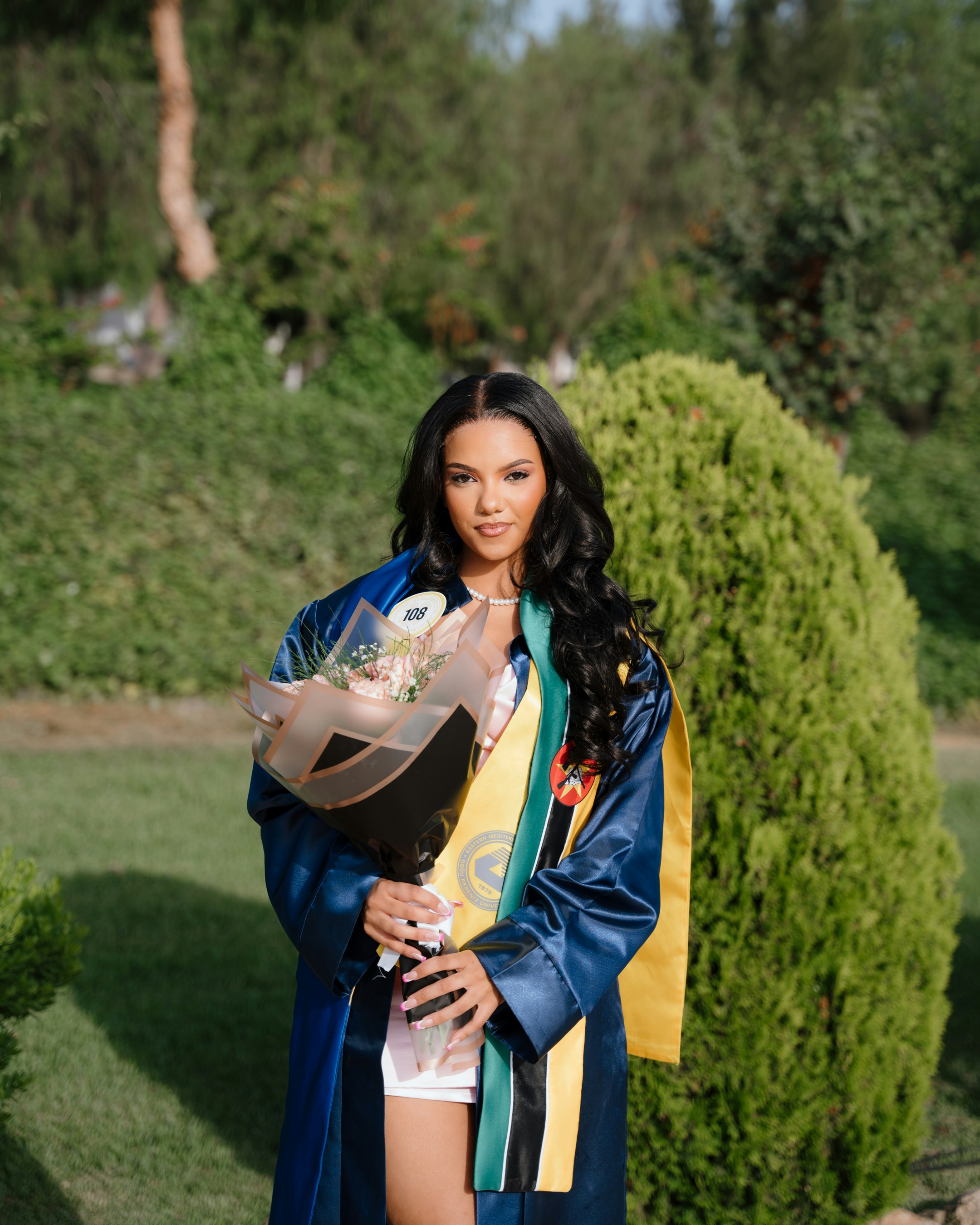 A woman in graduation attire holding a bouquet of flowers photo – Free ...