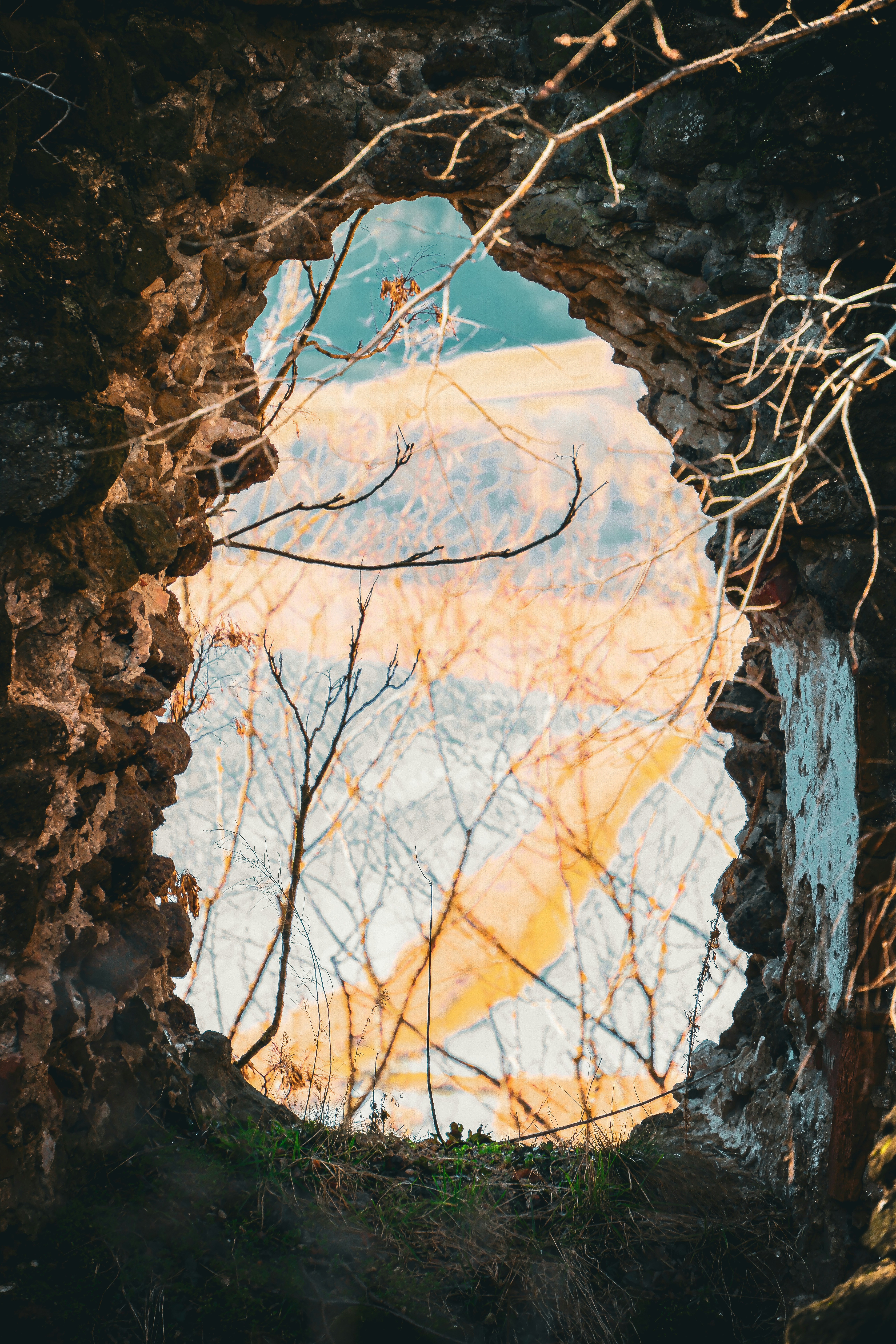 Vista attraverso un arco di pietra di un campo al tramonto.