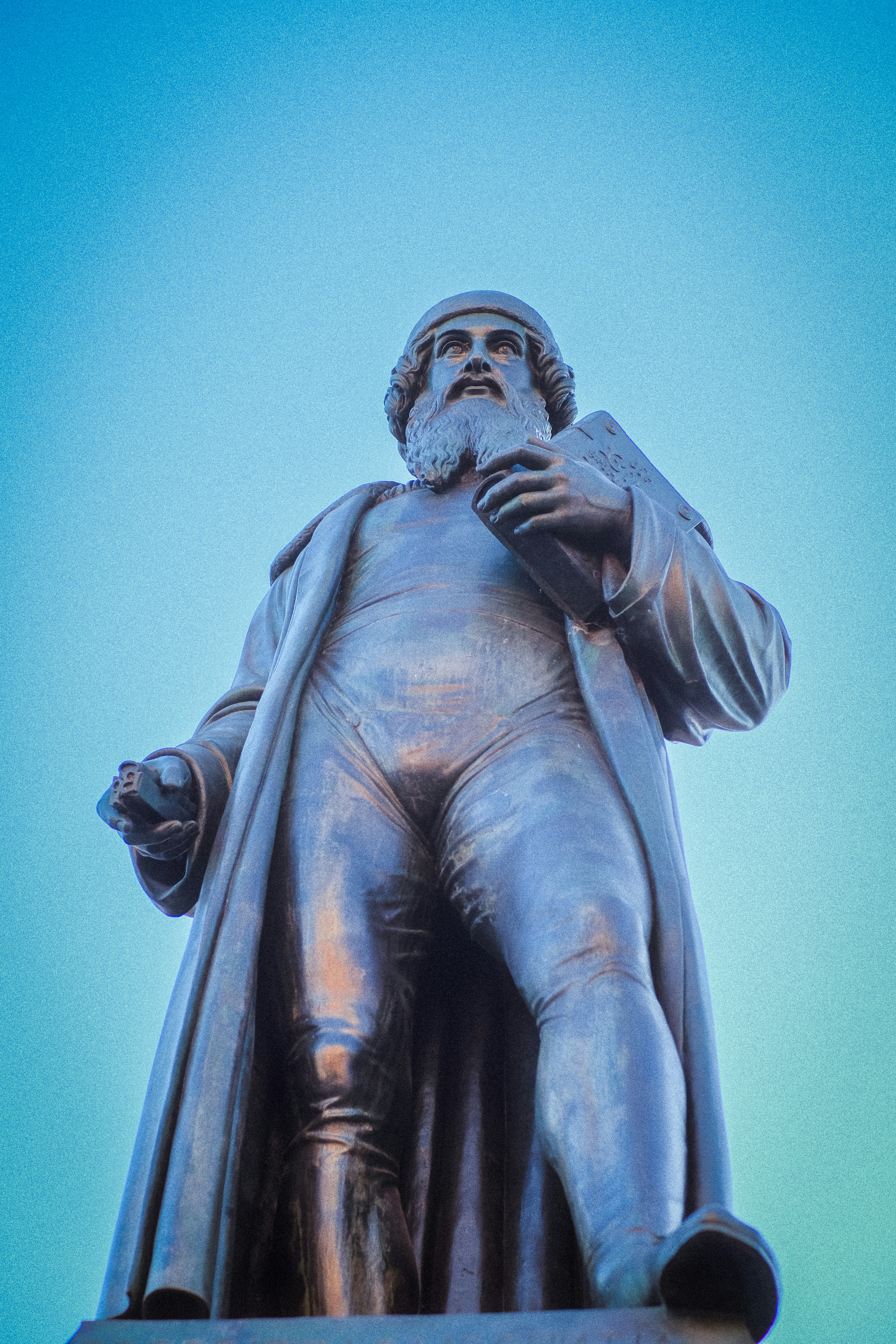 A bronze statue of a man holding a book