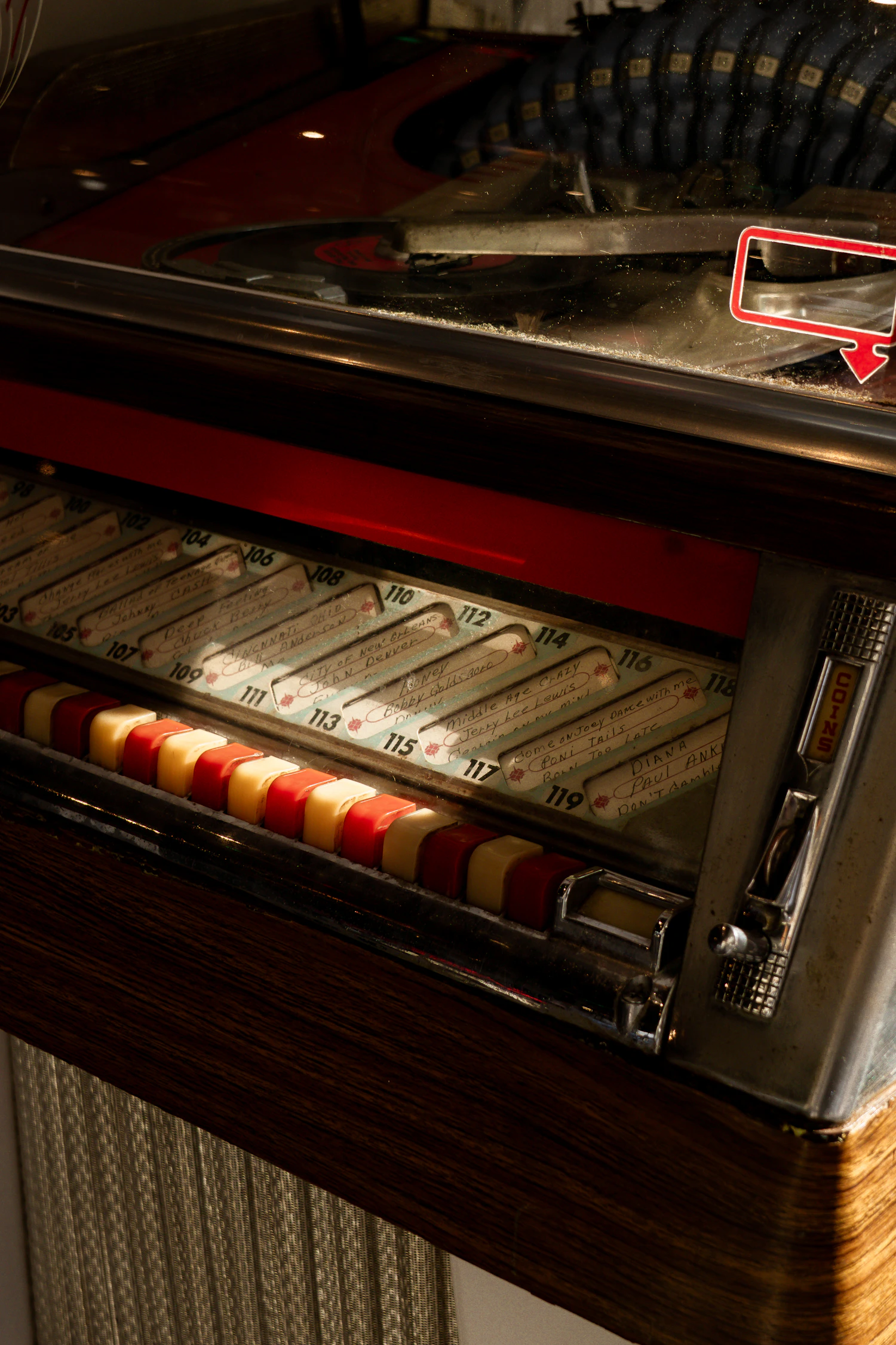 Close-up of a glowing jukebox selector with rows of coloured title strips