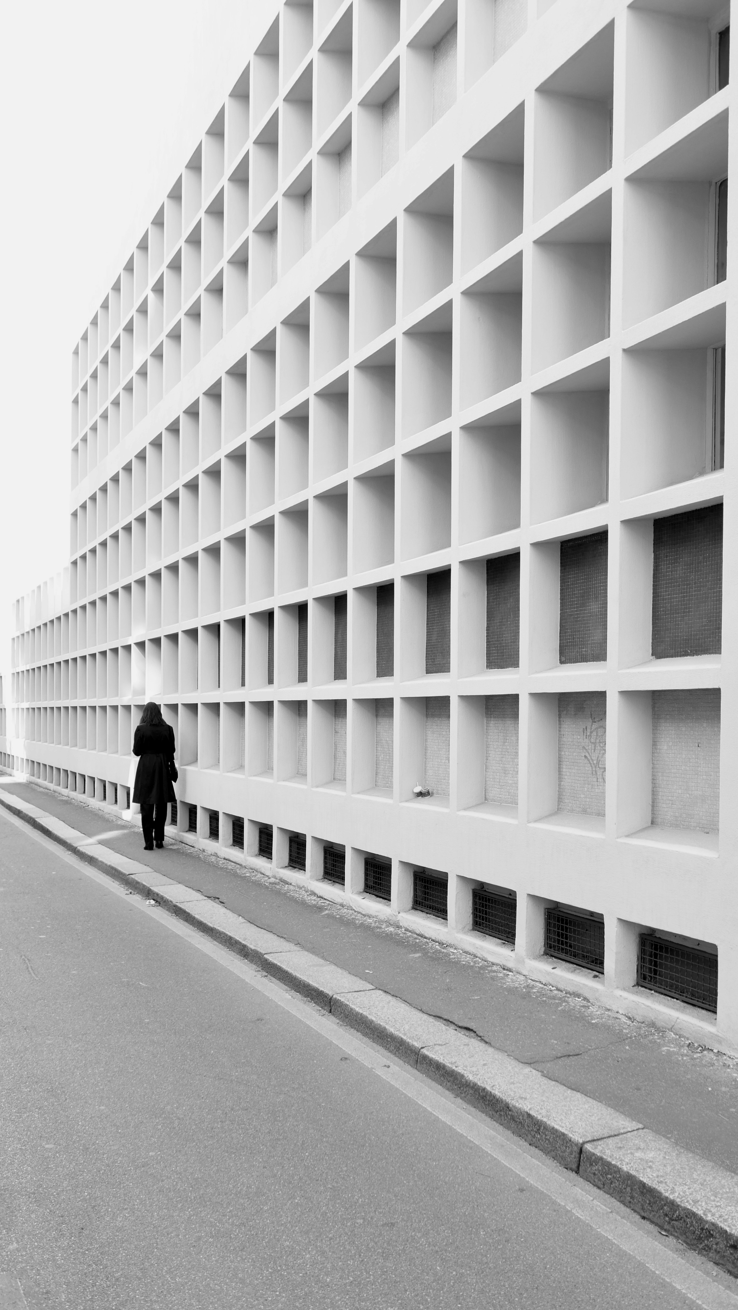 Una persona passa davanti a una facciata a griglia.