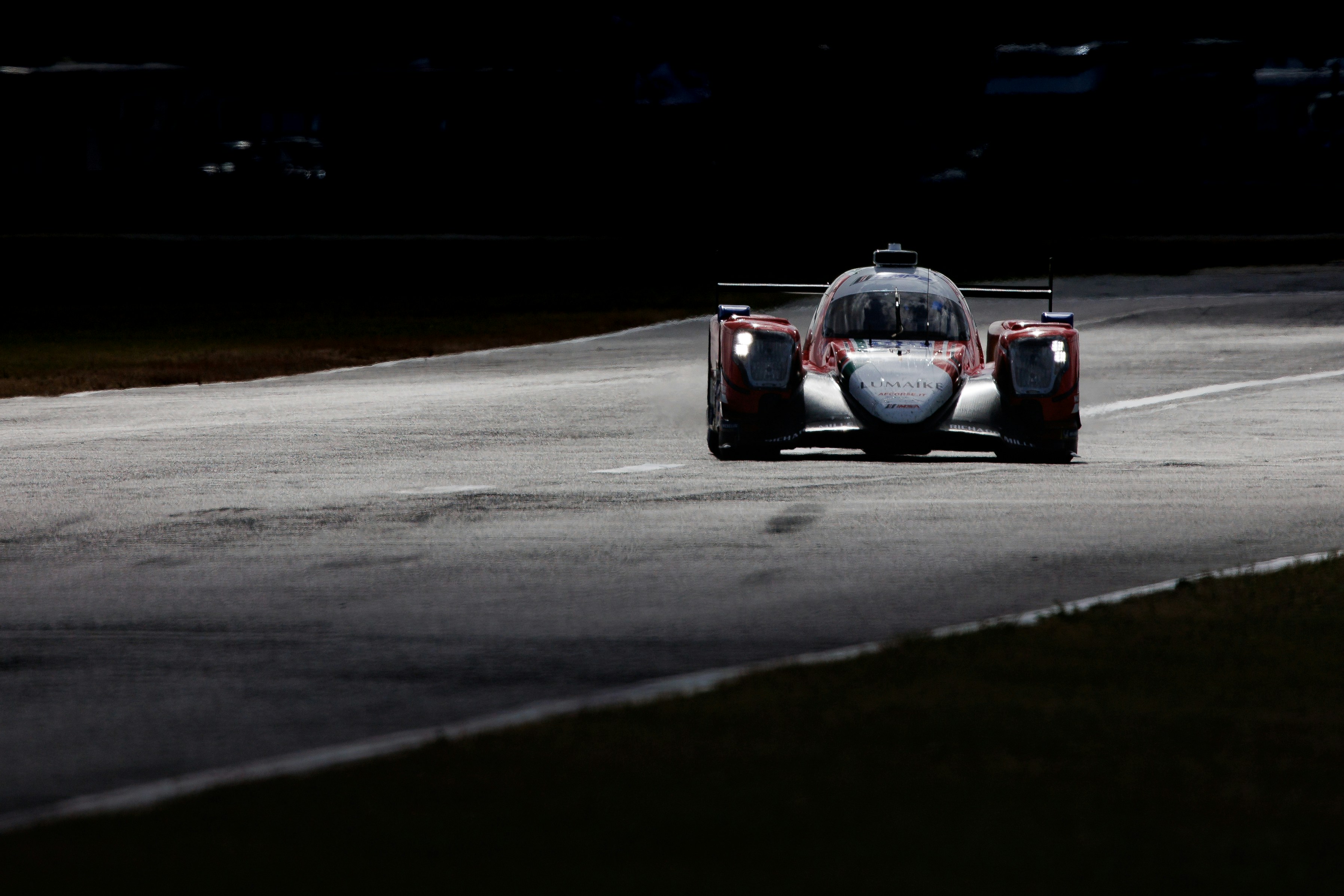 Race car speeding on a dark track at night.